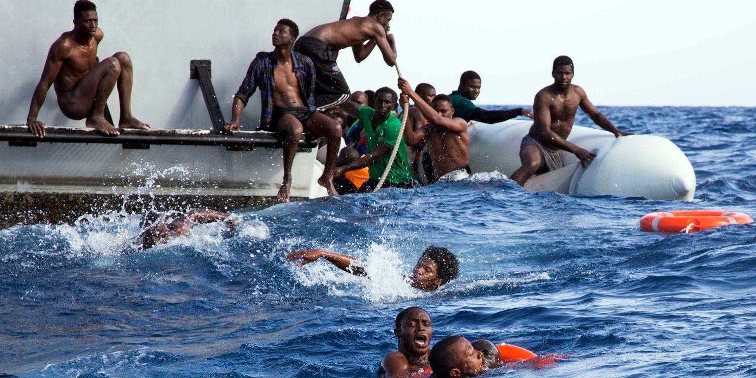 Migranter från en kapsejsad gummibåt försöker ta sig ombord från ett fartyg som tillhör den libyska kustbevakningen tidigare i november.