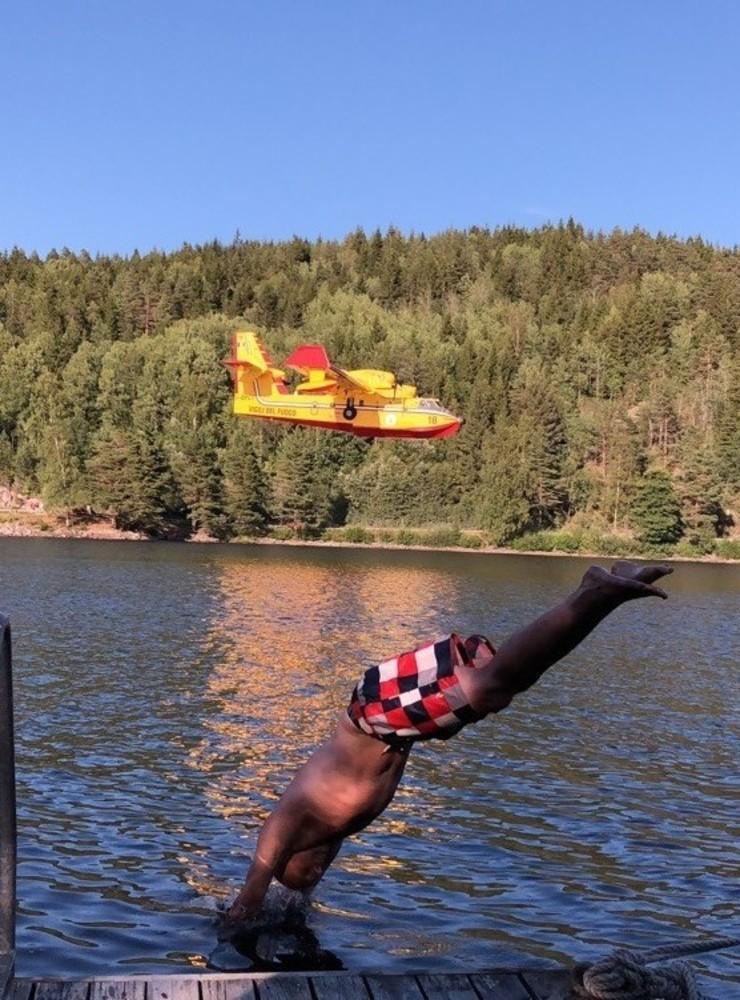 Min sommarbild föreställer min man Torbjörn som dyker i från vår brygga samtidigt som ett av de två italienska flygen som hjälpte till vid släckningsarbetet av skogsbranden på Kroppefjäll tisdag 24/7, flyger ner för att hämta en ny laddning vatten i Ragnerudssjön
