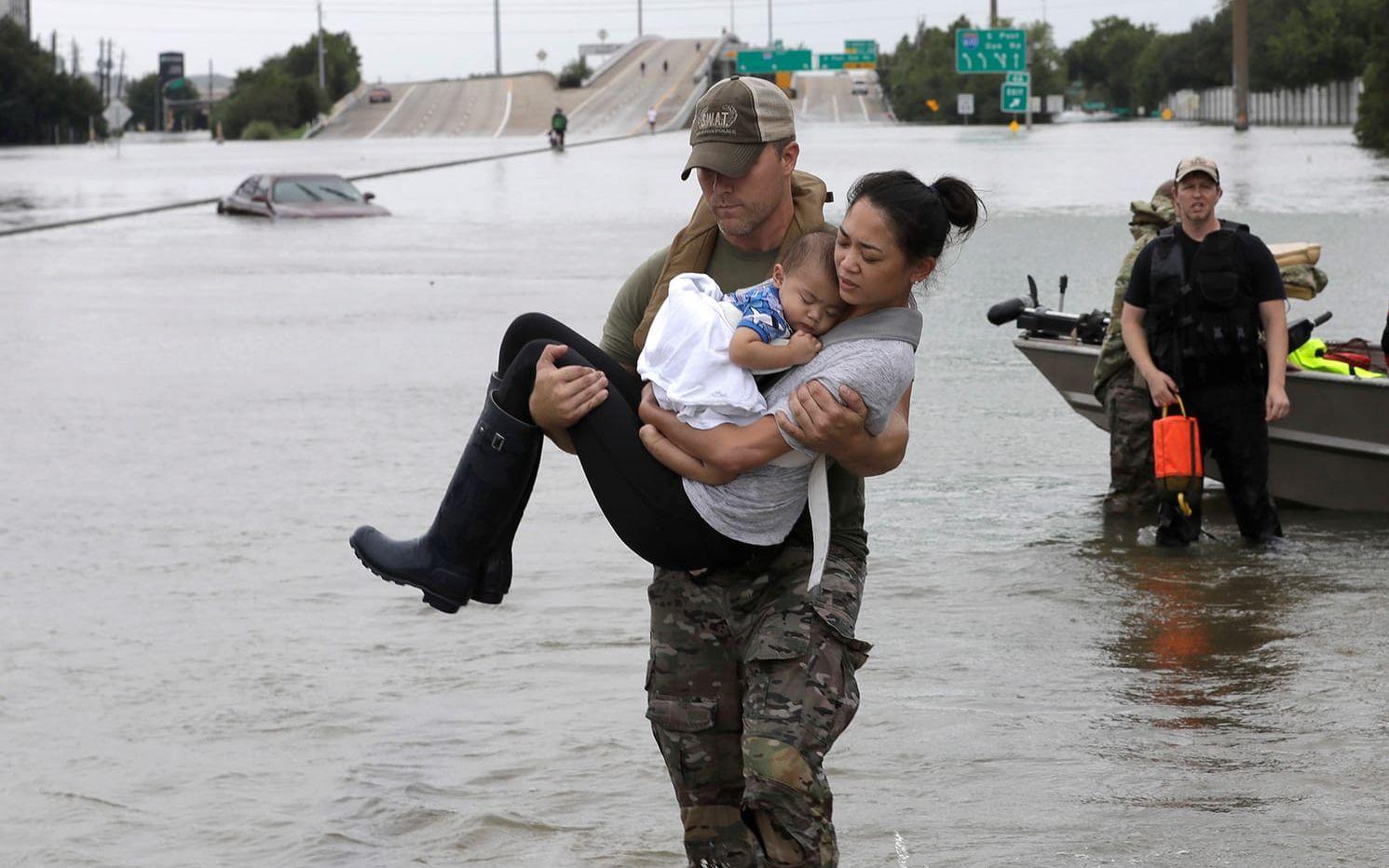 En medlem i Houston-polisens insatsstyrka bär en kvinna och hennes 13 månadet gamla son. FOTO: David J. Phillip/AP
