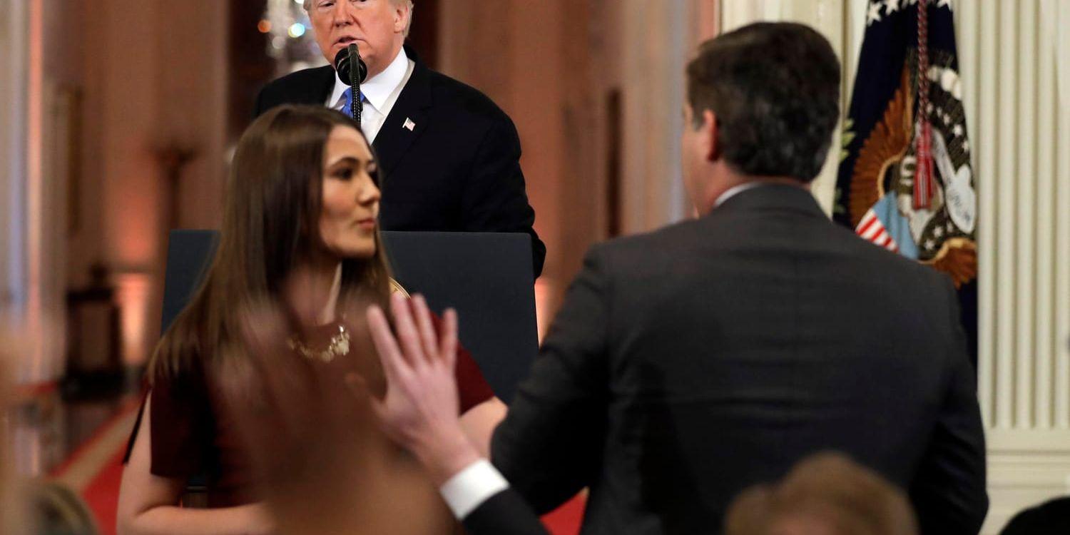President Donald Trump ser på när en praktikant försöker ta mikrofonen från CNN-journalisten Jim Acosta under pressträffen i Vita huset den 7 november.