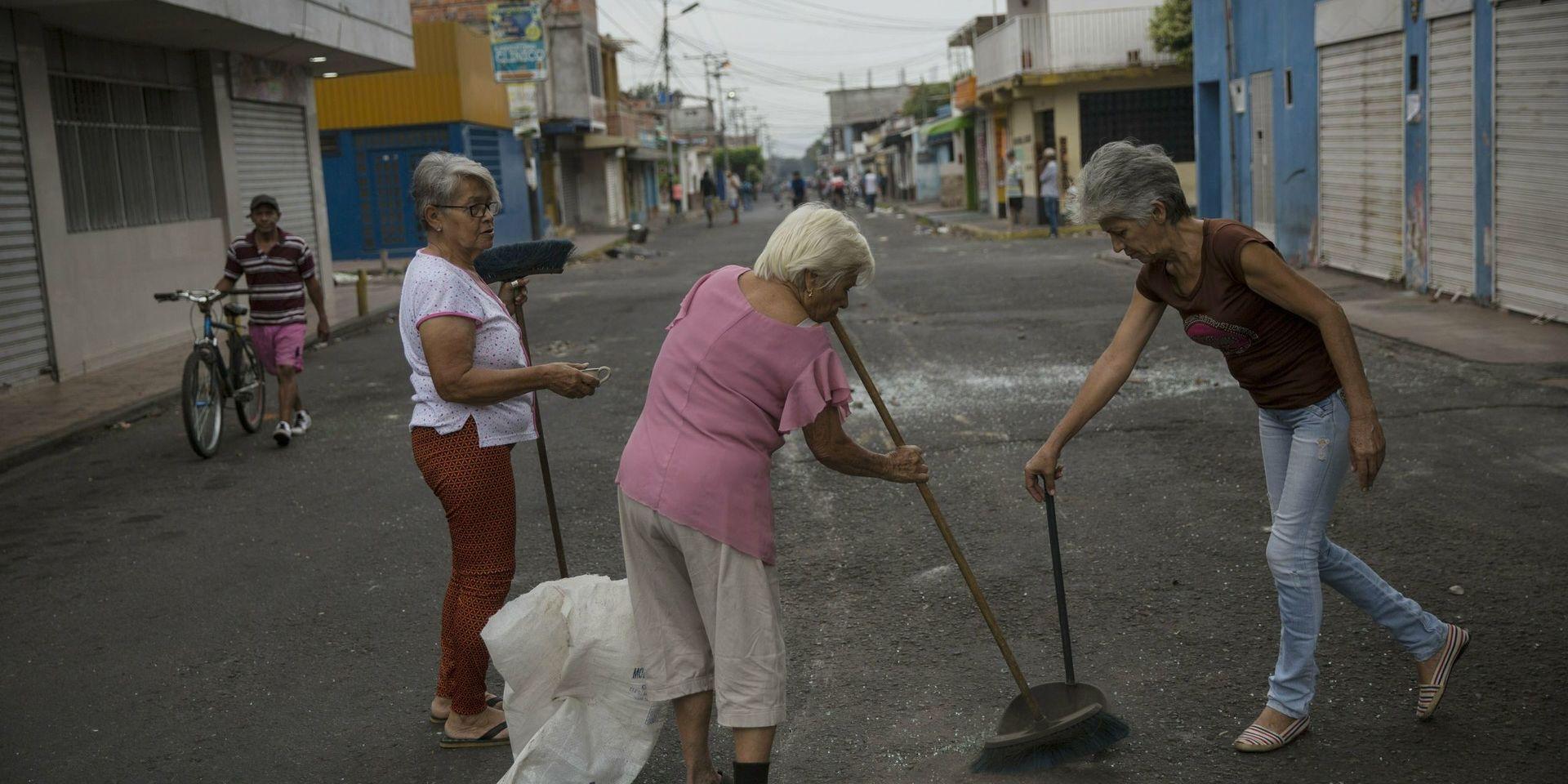 Neighbors clean the streets a day after clashes between anti-government protesters and the Bolivarian National Guard in Urena, Venezuela, near the border with Colombia, Sunday, Feb. 24, 2019. A U.S.-backed drive to deliver foreign aid to Venezuela on Saturday met strong resistance as troops loyal to President Nicolas Maduro blocked the convoys at the border and fired tear gas on protesters.  (AP Photo/Rodrigo Abd)