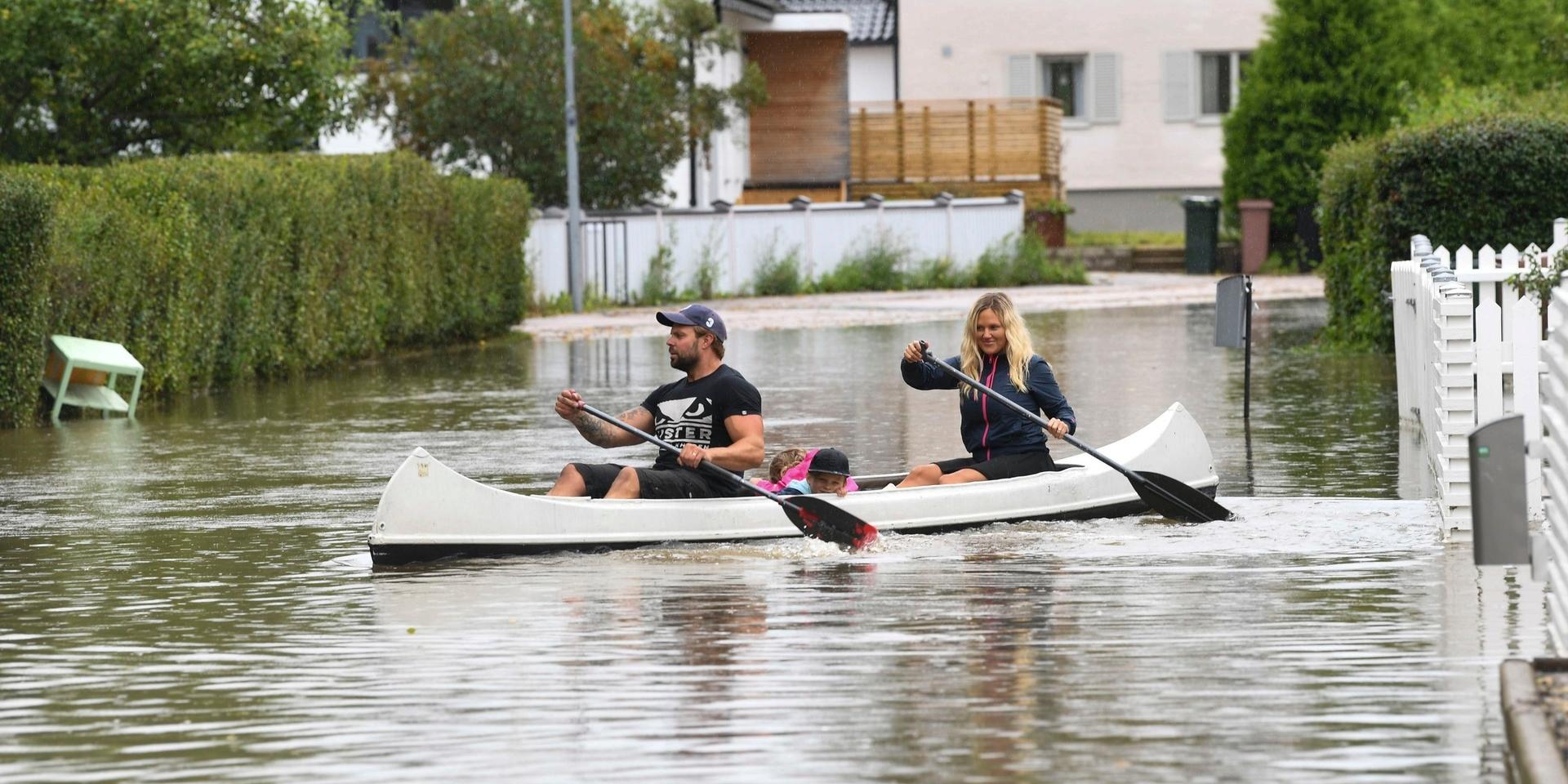 Barnen Melissa och Hero med föräldrarna Stina och Micke, paddlar kanot genom ett översvämmat villaområde efter nattens kraftiga skyfall.
