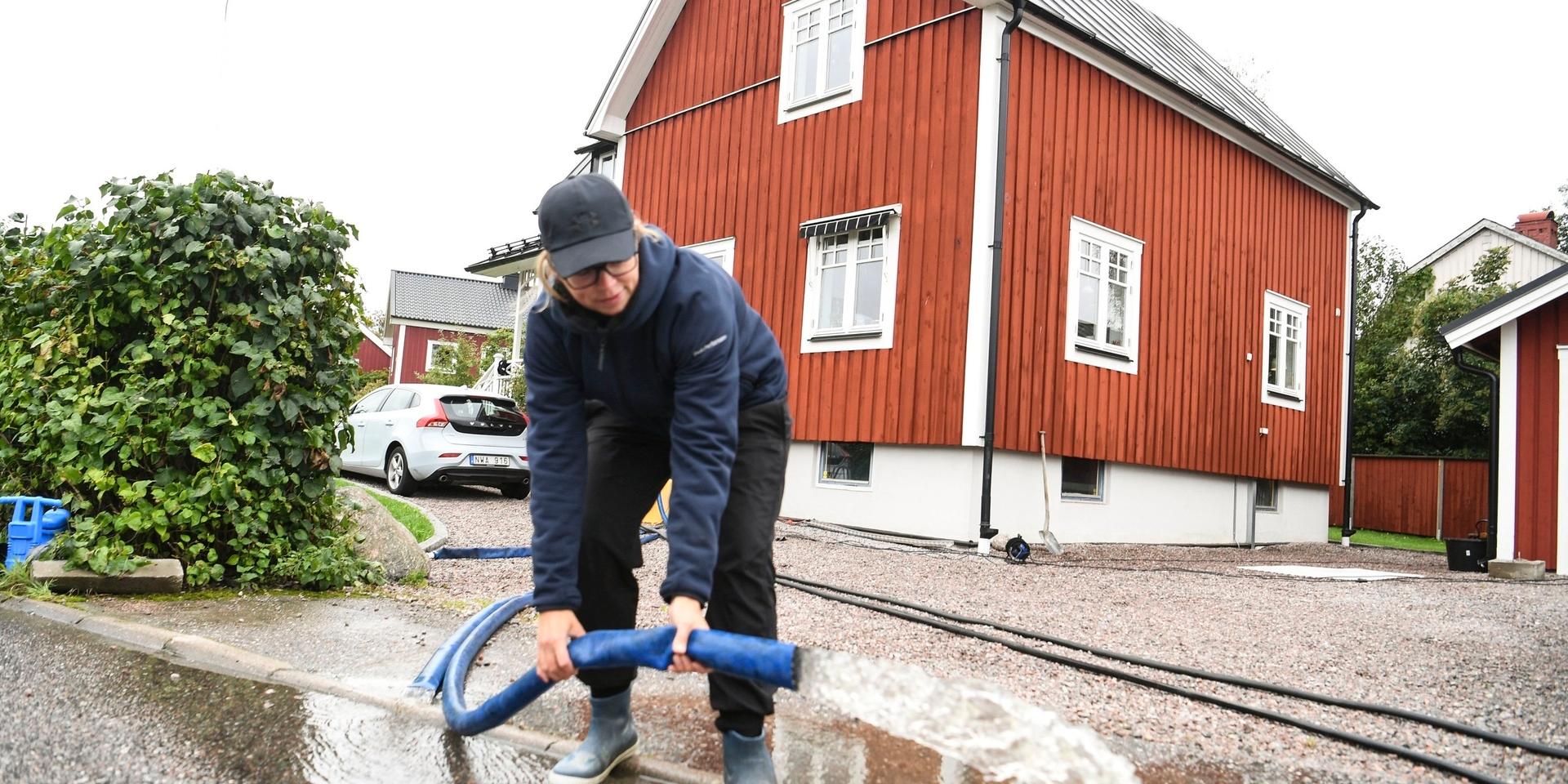 Maria Godås pumpar vatten från sin källare som har trängt igenom från översvämmade avlopp efter nattens kraftiga skyfall.