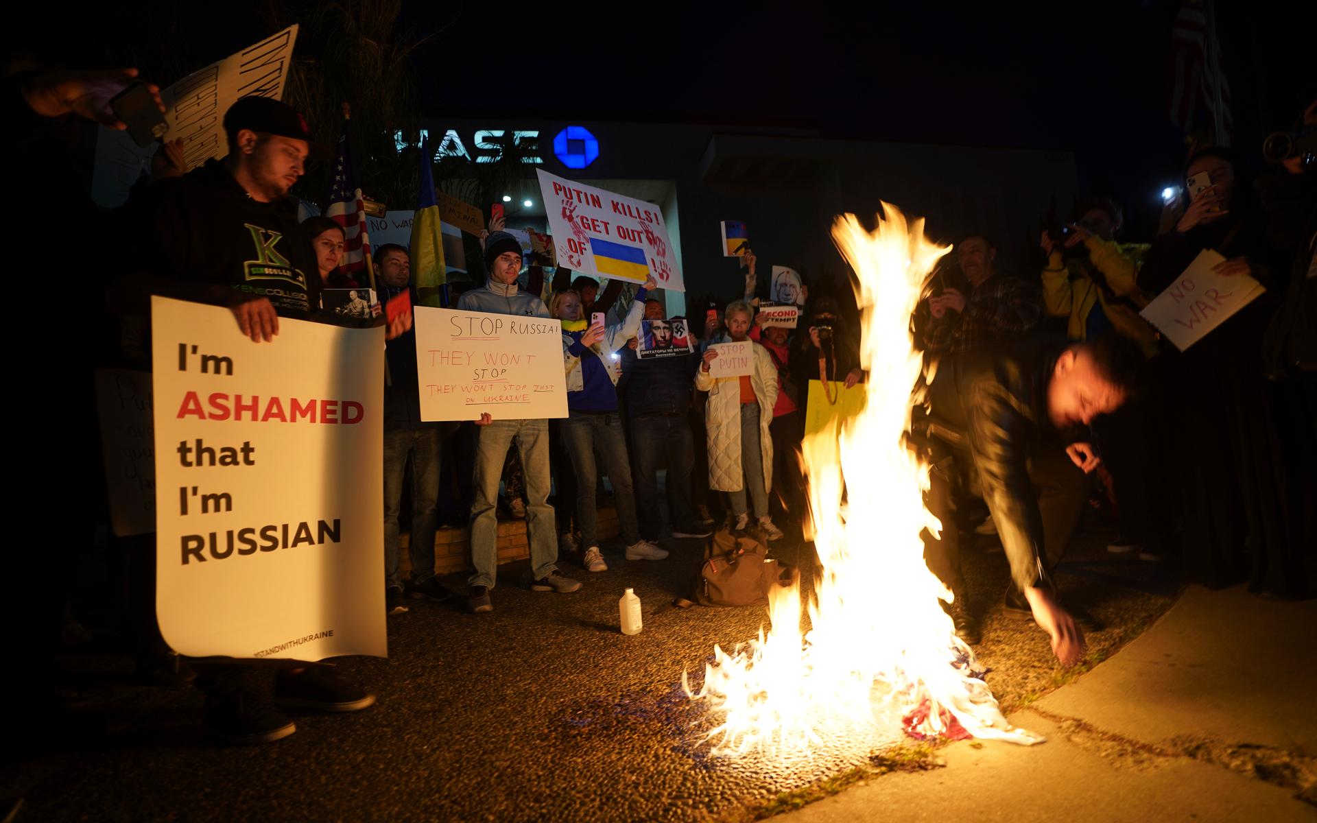 Ryska medborgare bränner upp en rysk flagga i protest mot invasionen. 