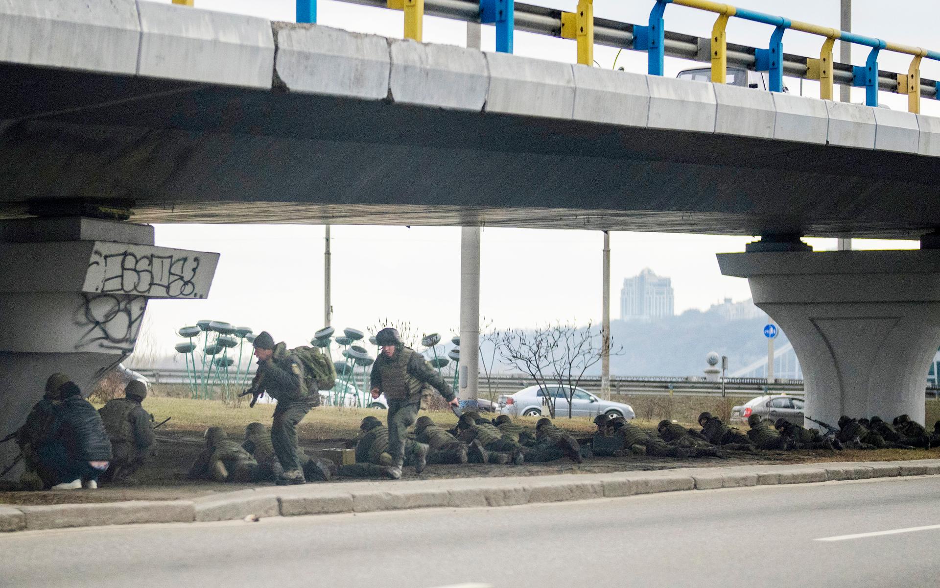 Ukrainska soldater tar betäckning under en bro under skottlossning inne i staden. 