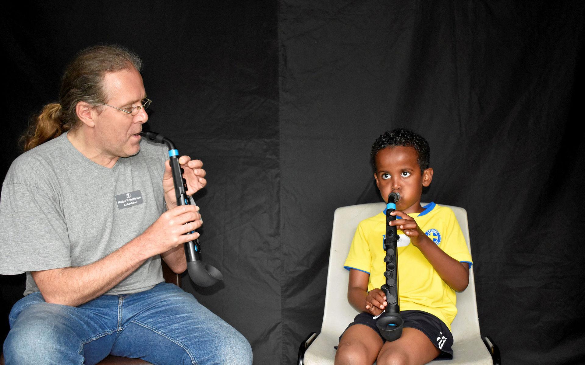 Musiklärare Niklas Robertsson lär sexåriga Mohammed Mahamad att spela saxofon.