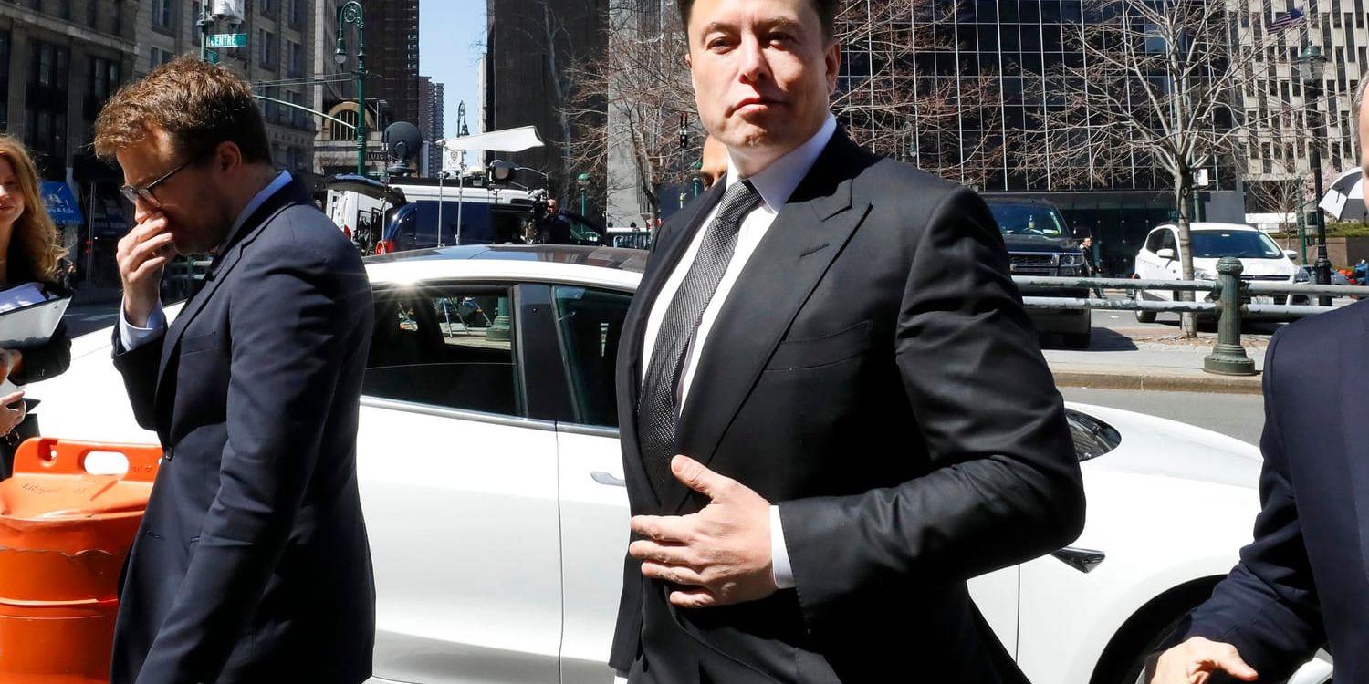 Elon Musk hävdar att Teslas bilar, här en Model 3 bakom honom, ska kunna ta sig fram i trafiken helt själva från och med nästa år. Bilden är från i april.