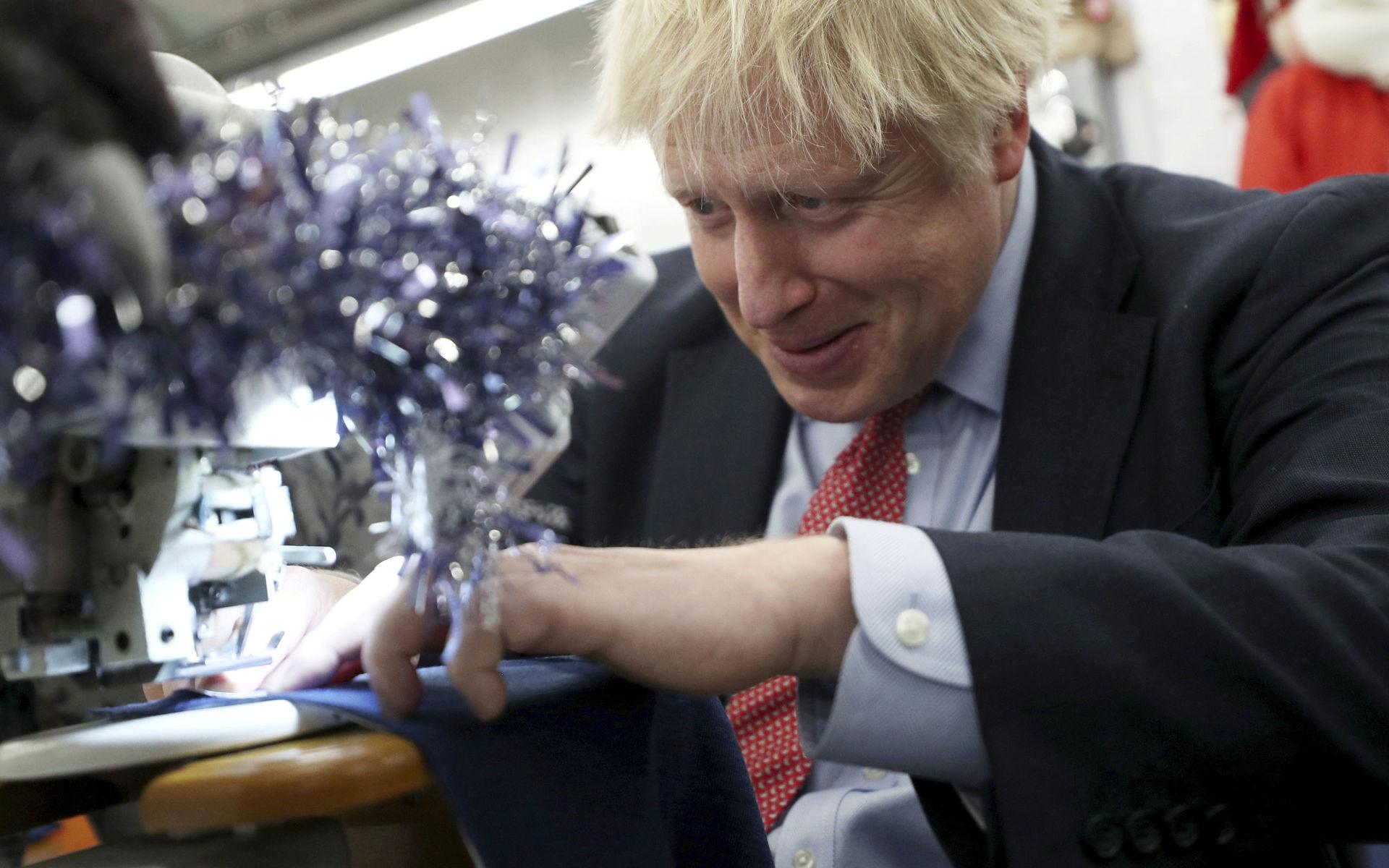 Britain&apos;s Prime Minister Boris Johnson tries to operate a sewing machine decorated for Christmas, during an election campaign stop at John Smedley Mill in Matlock, England, Thursday Dec. 5, 2019. The UK goes to the polls in a General Election on Dec. 12. (Hannah McKay/Pool via AP)  LRC105