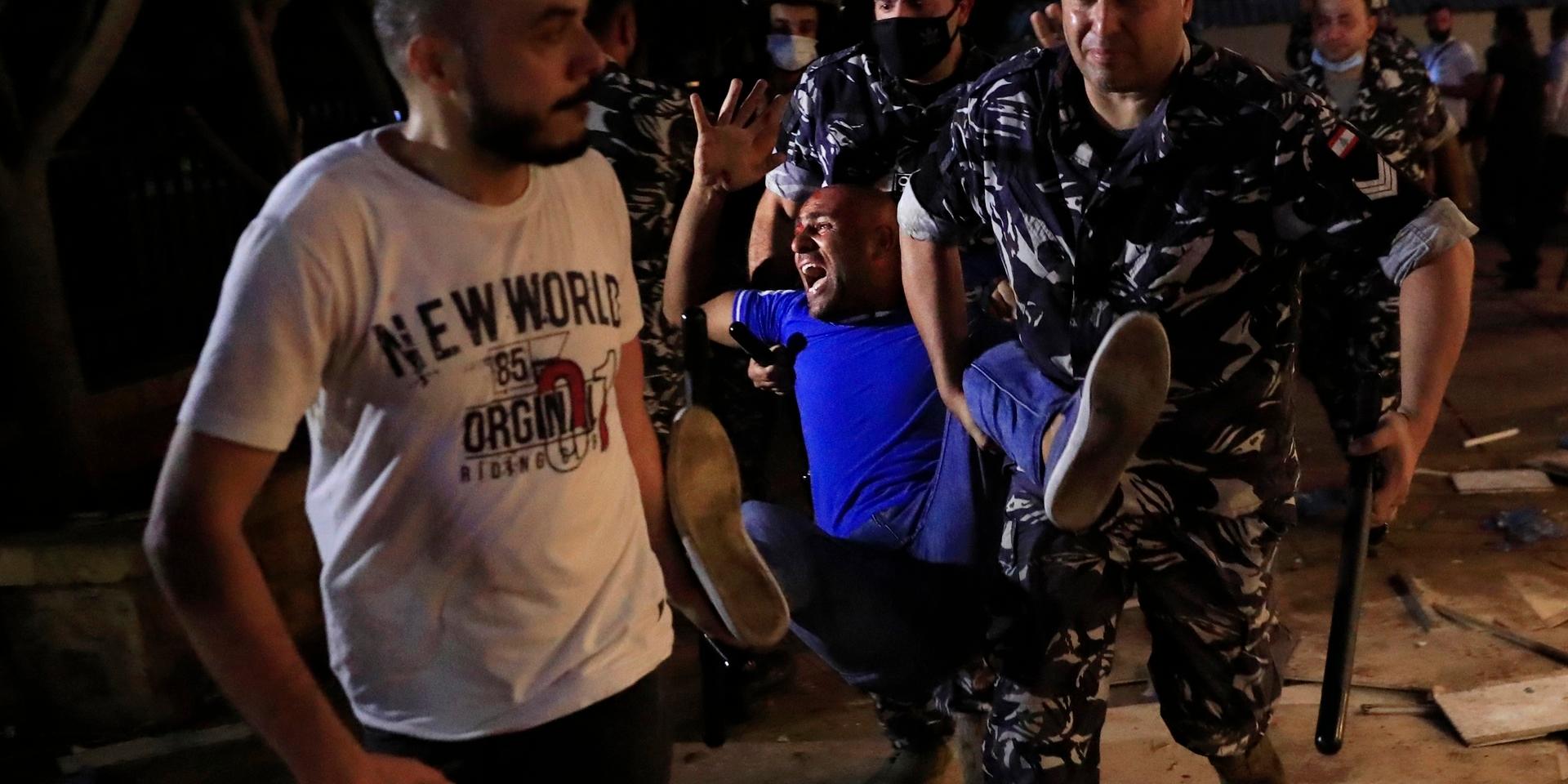 Polismän bär iväg en man som skadats i protester i Libanons huvudstad Beirut. Protesterna gäller vad som uppfattas som myndigheternas försök att förhindra en utredning av vad som låg bakom den omfattande explosionen. Arkivbild.