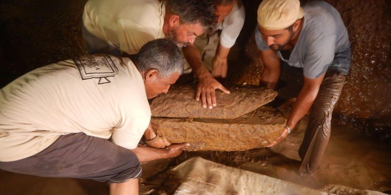 Här lyfter delar av teamet upp en av barnsarkofagerna av sandsten.