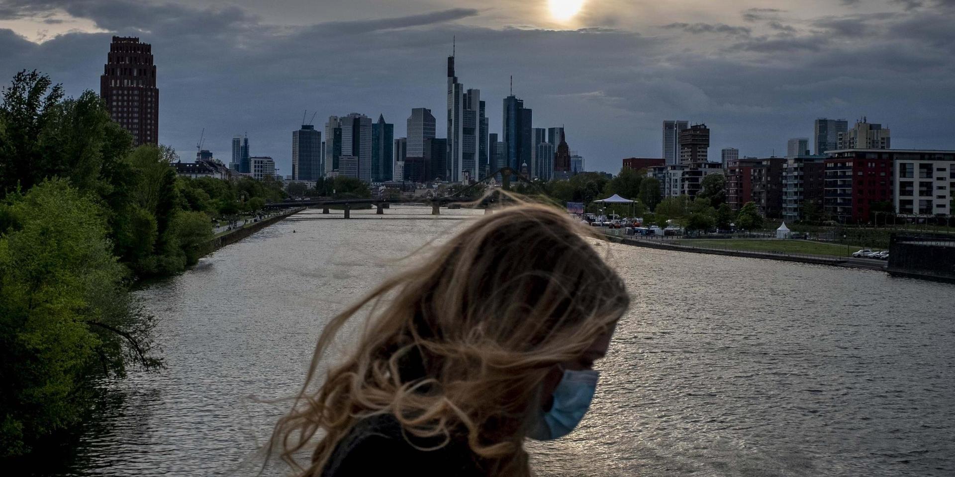 En kvinna med munskydd på en bro över floden Main i Frankfurt. Bilden är från i torsdags.