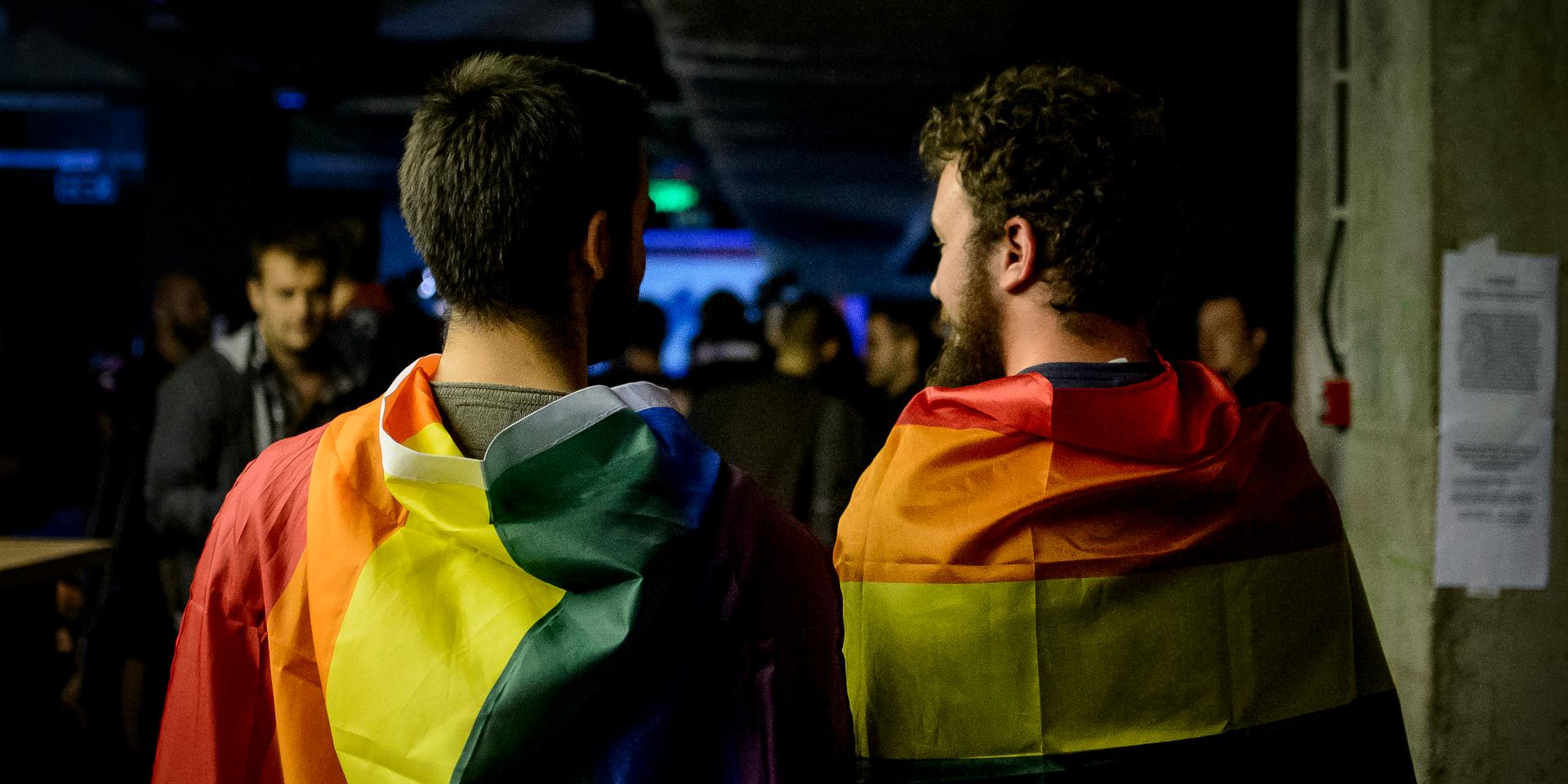 Two men draped in rainbow flags in a nightclub in Bucharest, Romania, Sunday, Oct. 7, 2018. Polls have closed in Romania after two days of voting on a constitutional amendment that would make it harder to legalize same-sex marriage. But the weekend referendum to redefine marriage failed to attract large numbers of voters and risk being voided. (AP Photo/Andreea Alexandru)