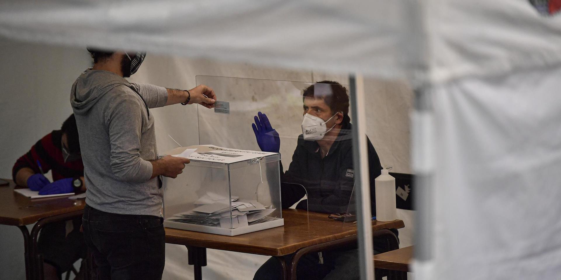 En väljare visar sitt id-kort vid en vallokal i Baskien. 