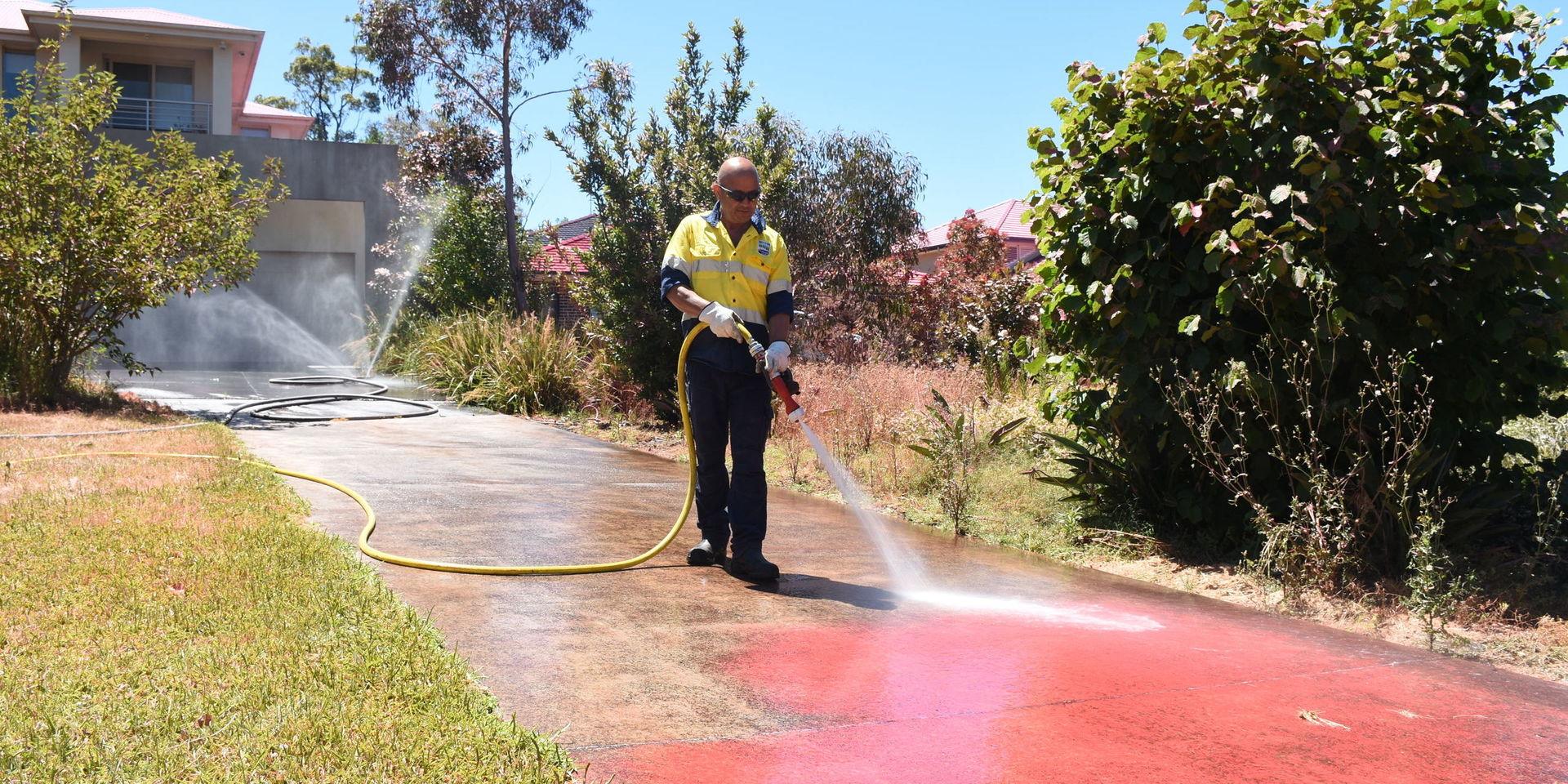 Det rosa medlet som användes vid vattenbombningen spolas bort dagen efter att brandrisken i delar av New South Wales nådde katastrofläge.