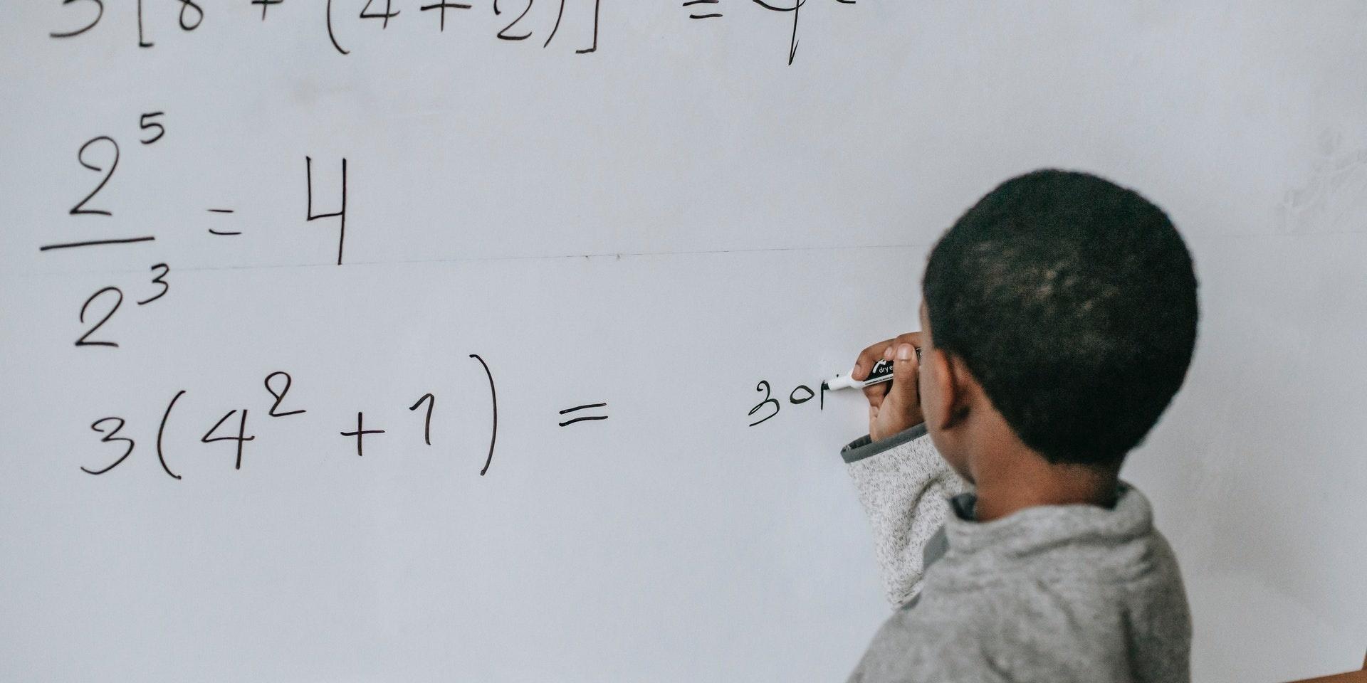 Pojke löser matematiska tal i ett klassrum