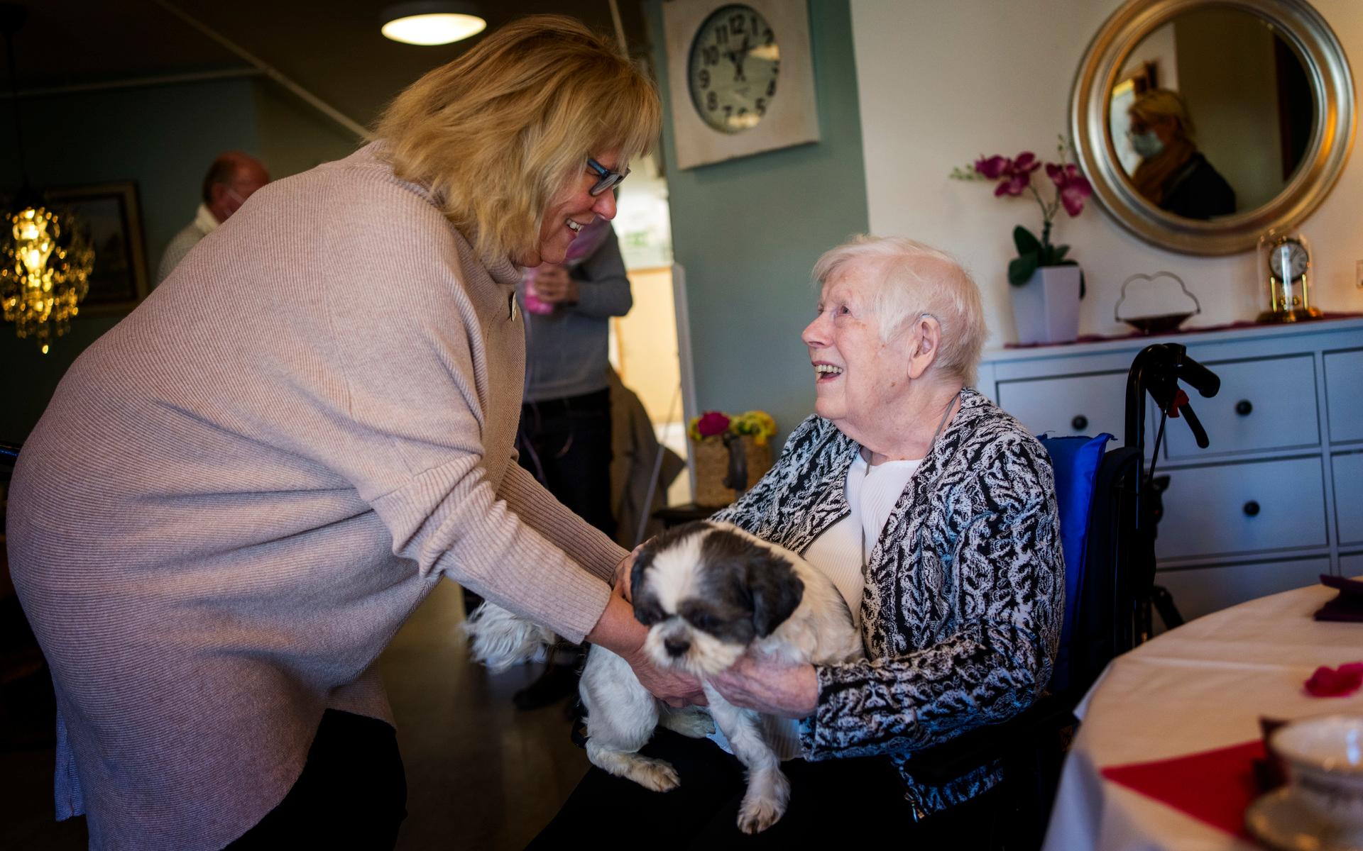 Enhetschefen Inger Larsson hjälper upp hunden Ella i Ruths knä. Ella är populär bland de boende och tassar vant runt bland borden i den gemensamma matsalen.