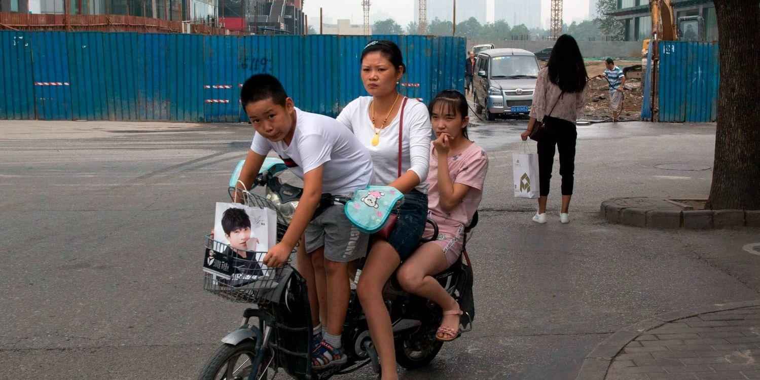 En kvinna och hennes två barn på en elmoped i Peking i juli i år. Elfordonen blir allt fler i Kinas städer, men det har ännu inte fått bukt med föroreningarna.
