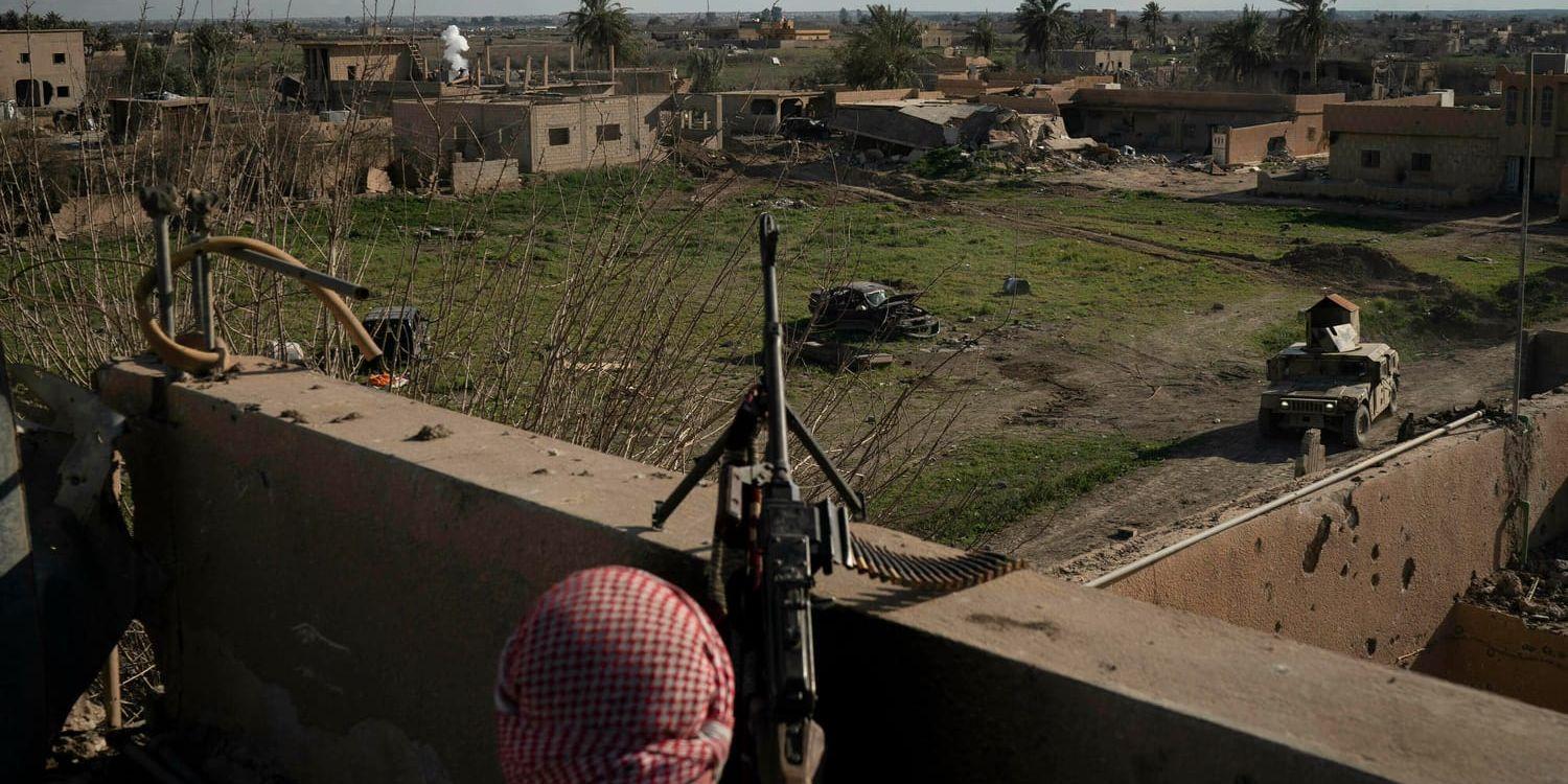 En soldat från alliansen SDF på ett tak nära den del av byn Baghouz i östra Syrien som fortfarande hålls av IS.
