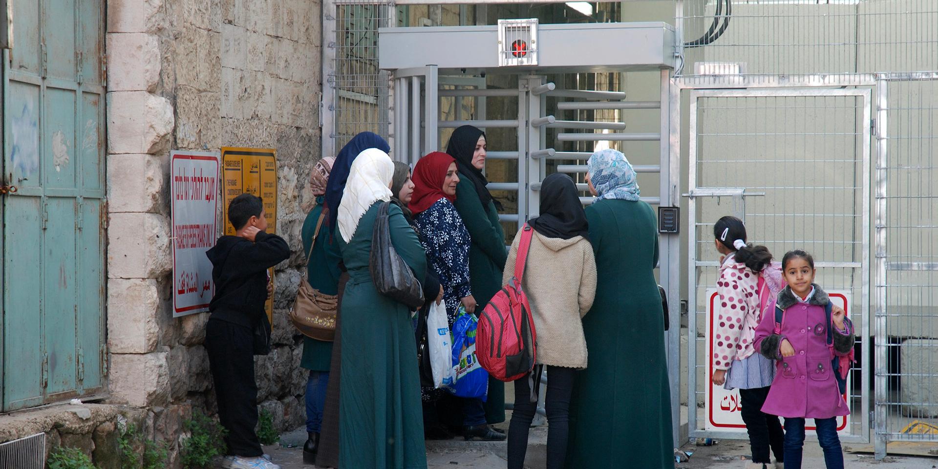 Palestinska lärare och barn köar på väg till skolan vid israelisk vägkontroll i Hebron, Shuhadagatan. 