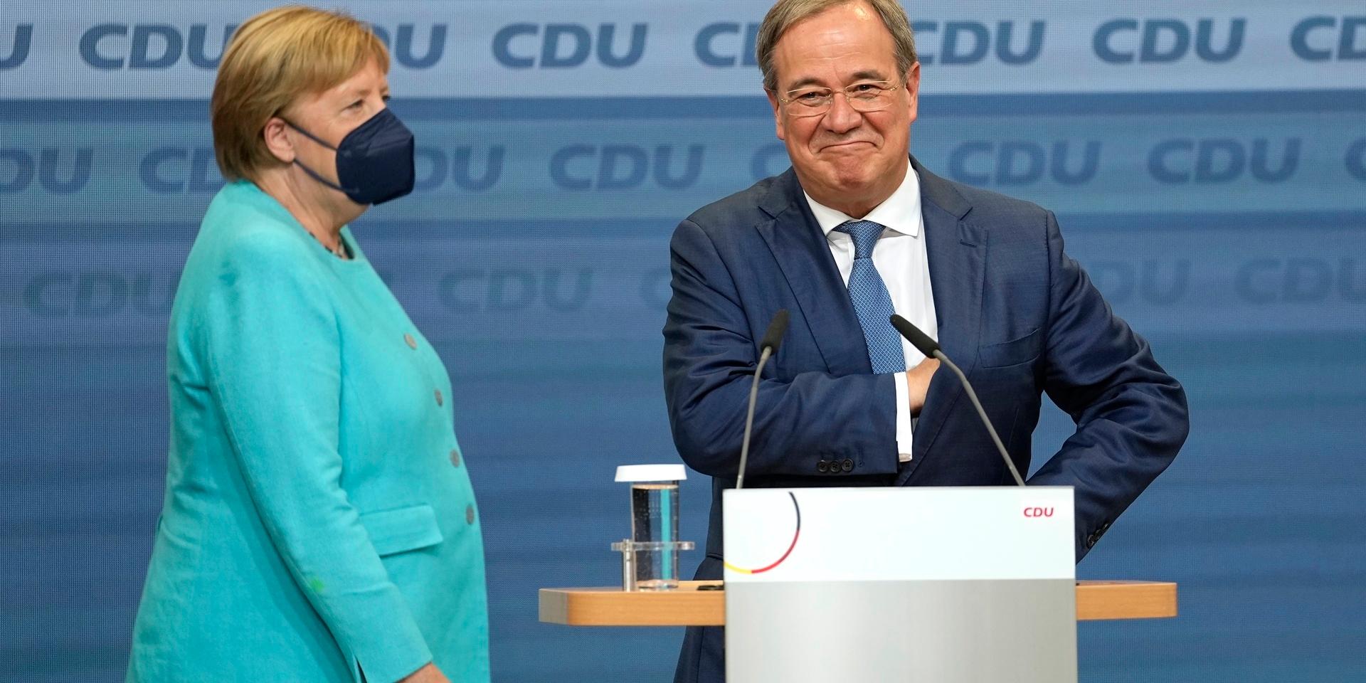 Chancellor Angela Merkel stands next to Governor Armin Laschet, right, the top CDU candidate after the German parliament elections at the Christian Democratic Union, CDU, party's headquarters in Berlin, Sunday, Sept. 26, 2021. German voters are choosing a new parliament in an election that will determine who succeeds Chancellor Angela Merkel after her 16 years at the helm of Europe's biggest economy. (AP Photo/Martin Meissner)  XVG112