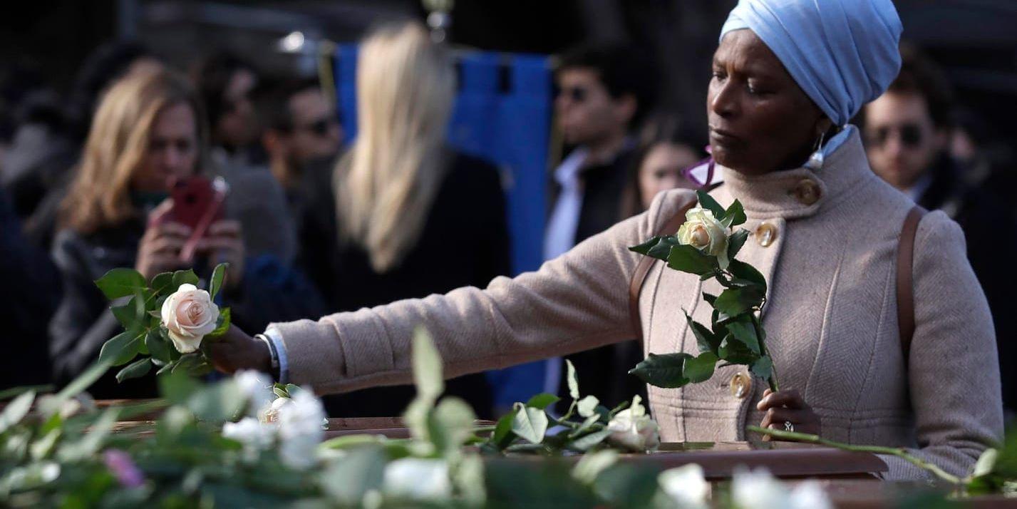En kvinna lämnar rosor på kistorna under en begravningsceremoni för 26 nigerianska kvinnor i staden Salerno i södra Italien.