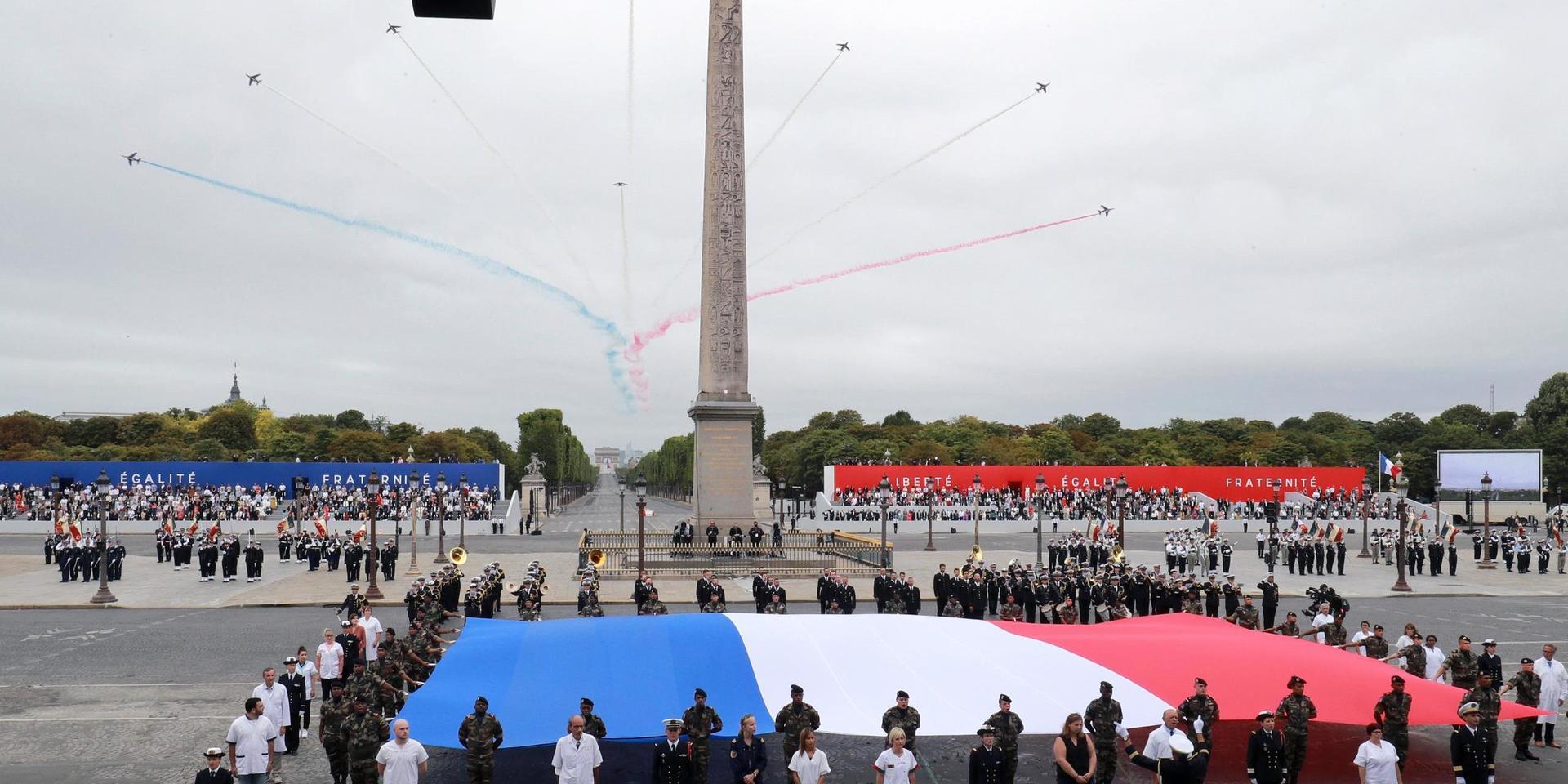Vårdanställda tog plats vid den franska flaggan under årets decimerade nationaldagafriande vid Place de la Concorde i Paris. 