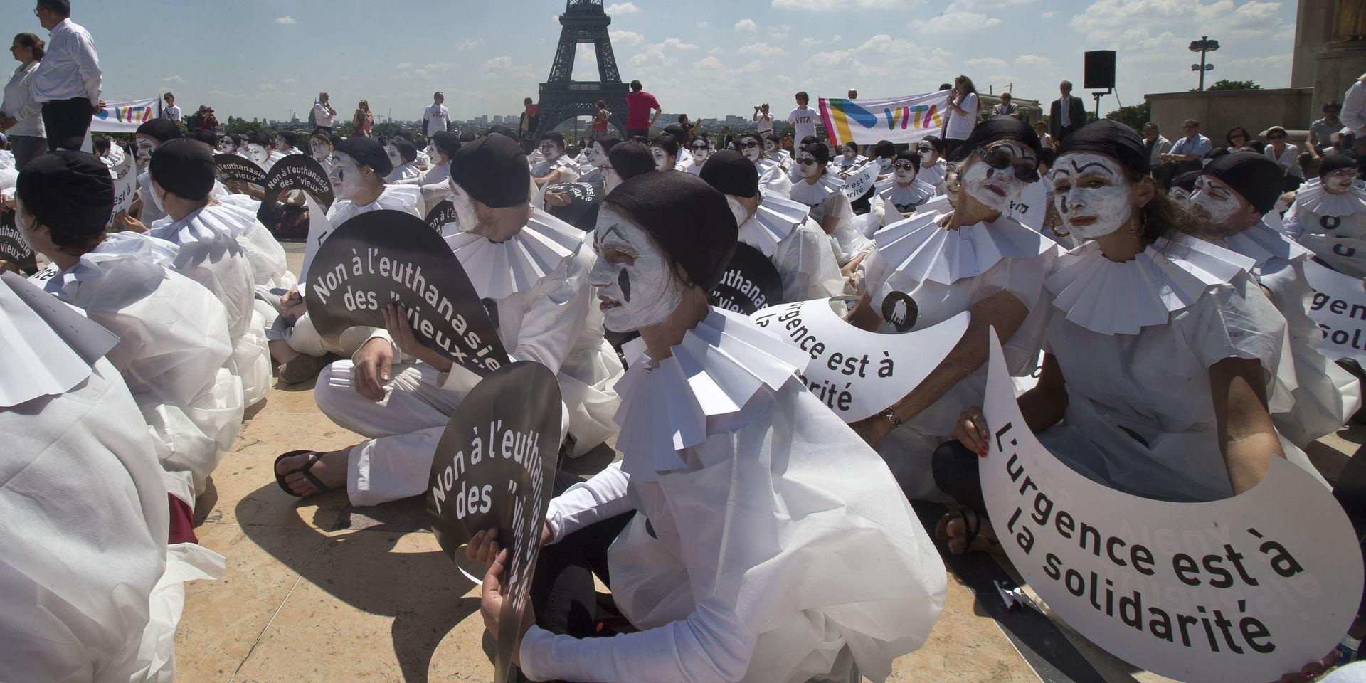 Demonstranter utklädda till mimare håller skyltar med texten 'Nej till dödshjälp för 'gamla'' vid en manifestation i Paris. Arkivbild.