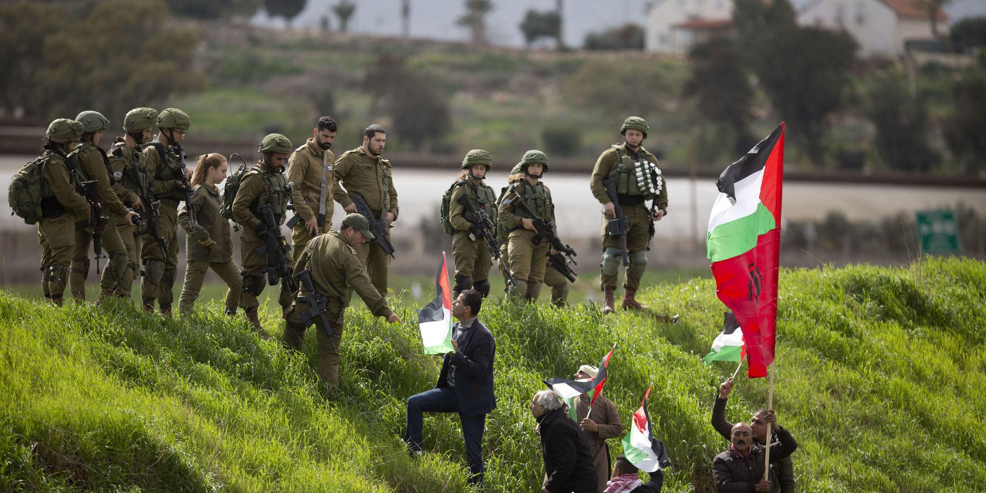 Palestinian demonstrators hold a national flag in front of Israeli forces as they protest against U.S. President Donald Trump&apos;s Mideast initiative, near a Jewish settlement Beqa&apos;ot in Jordan Valley in the West Bank, Saturday, Feb. 29, 2020. (AP Photo/Majdi Mohammed).  MJ106