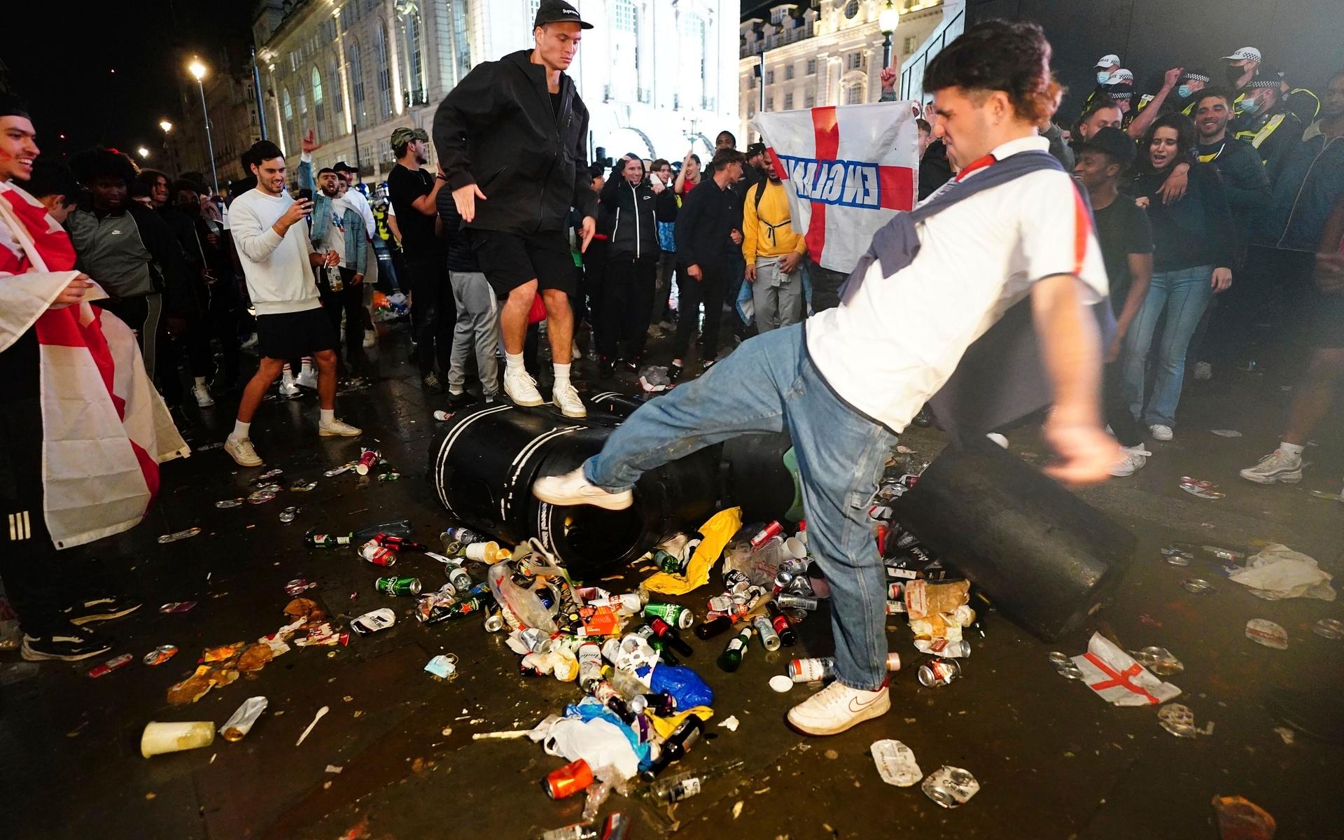Engelska fans sparkar på soptunnor vid Piccadilly Circus, i London.