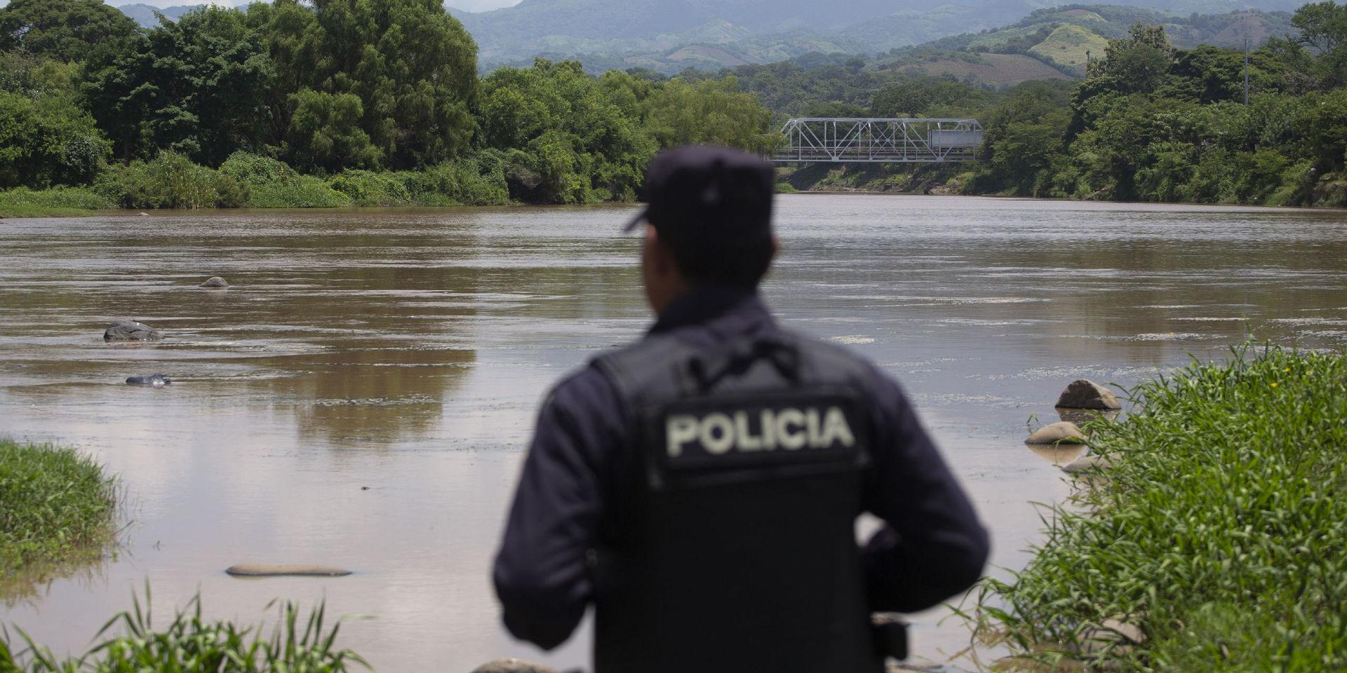 En polis i El Salvador ser ut över en flod vid gränsen mot Guatemala. Arkivbild. 