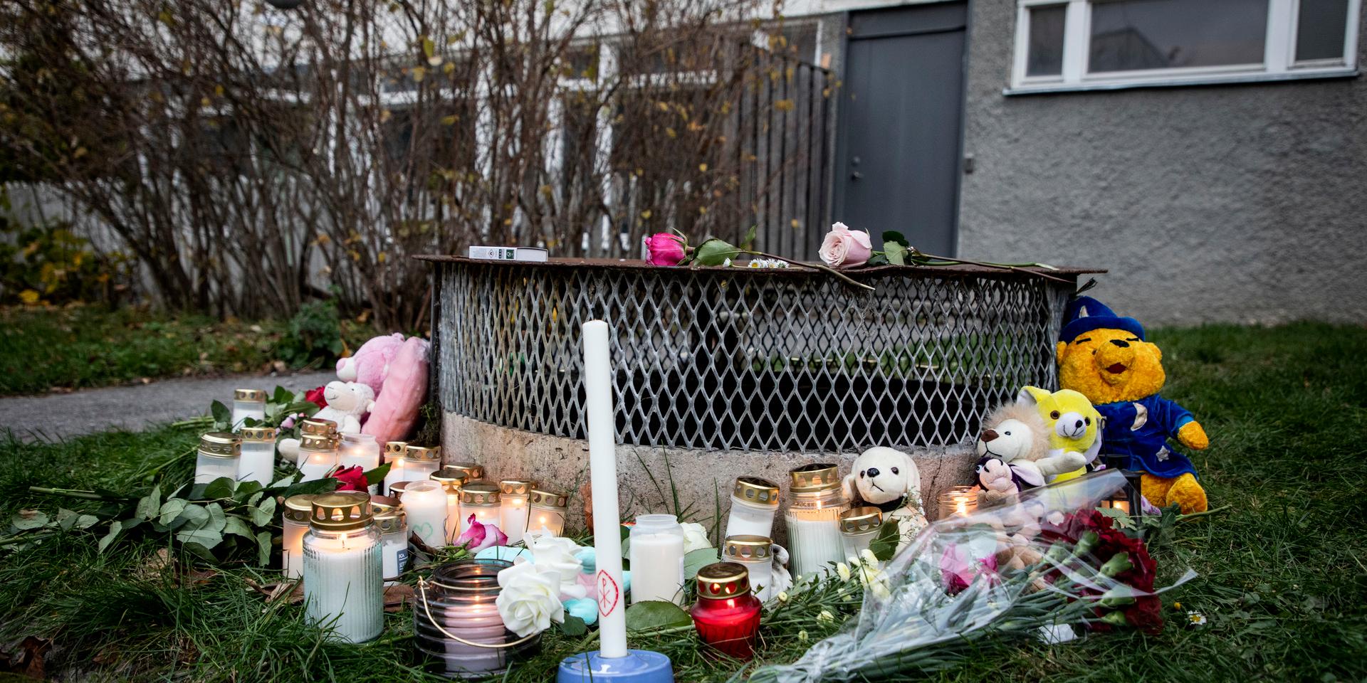 Gosedjur, blommor och ljus vid den plats där de två barnen hittades med livshotande i Hässelby i november förra året. Ett av barnen avled senare av sina skador. Arkivbild.