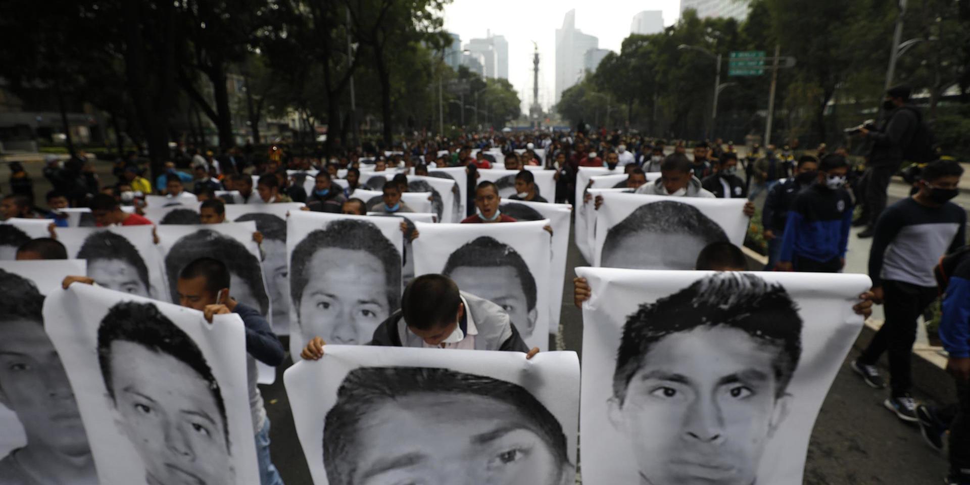 Demonstranter och anhöriga håller upp bilder på de 43 studenter som fördes bort 2014. 