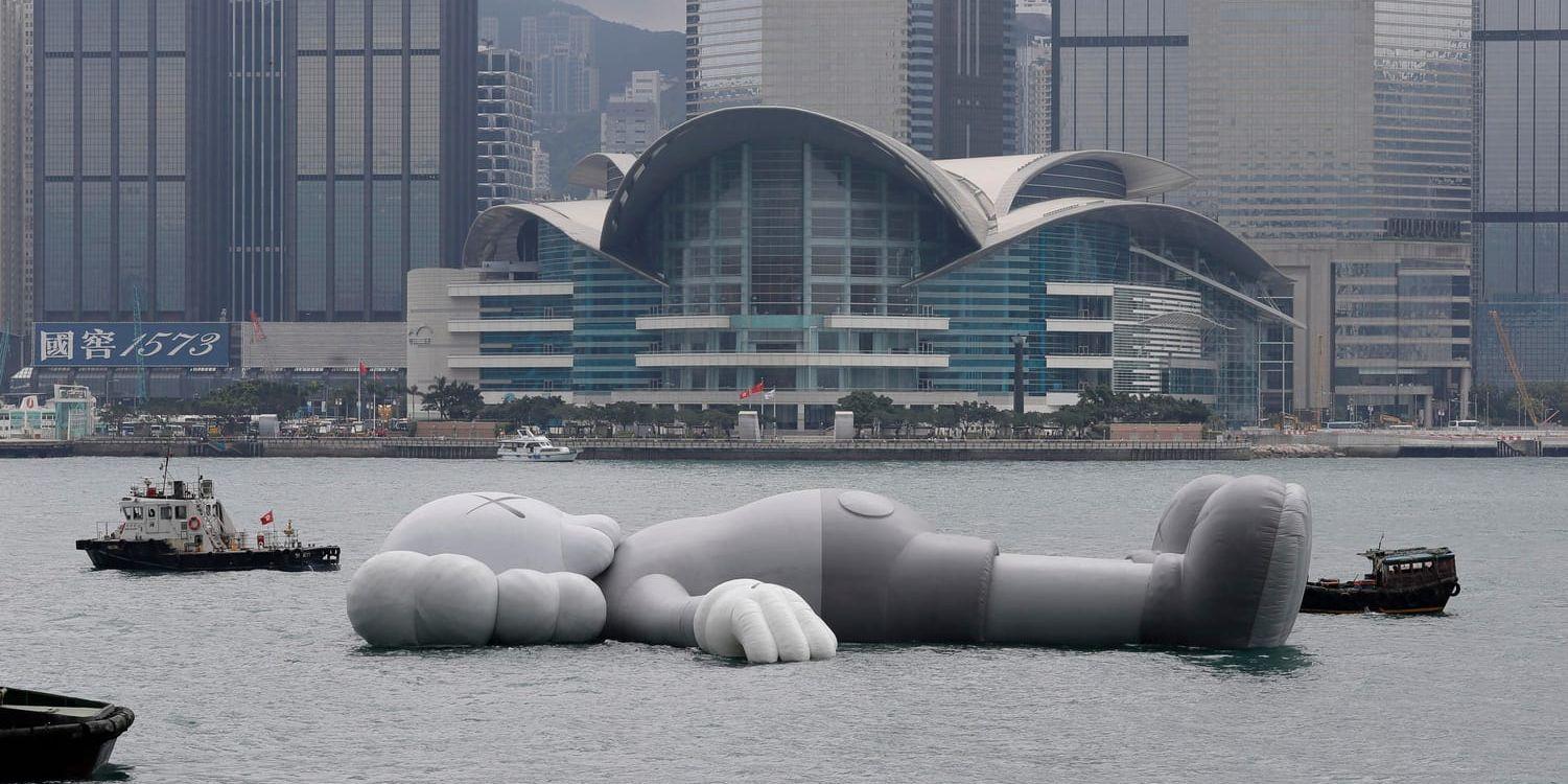 Skulpturen "Kaws:Holiday' bogseras in i Victoriahamnen i centrala Hongkong.,