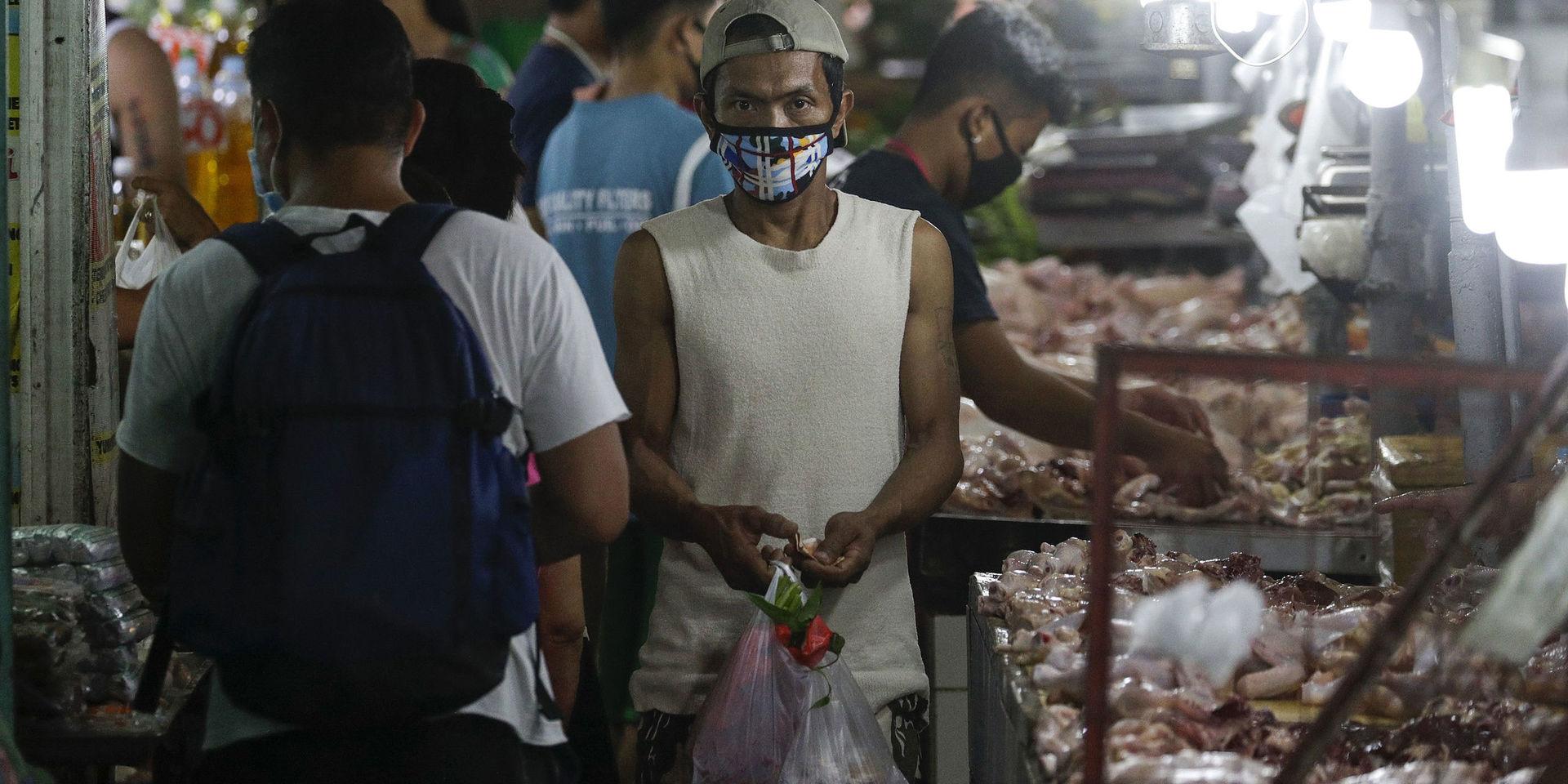 En man bär ansiktsmask på marknaden. Megastäder som filippinska Manila, där människor bor tätt och fattigdomen är utbredd, är en tacksam grogrund för smittspridning. 