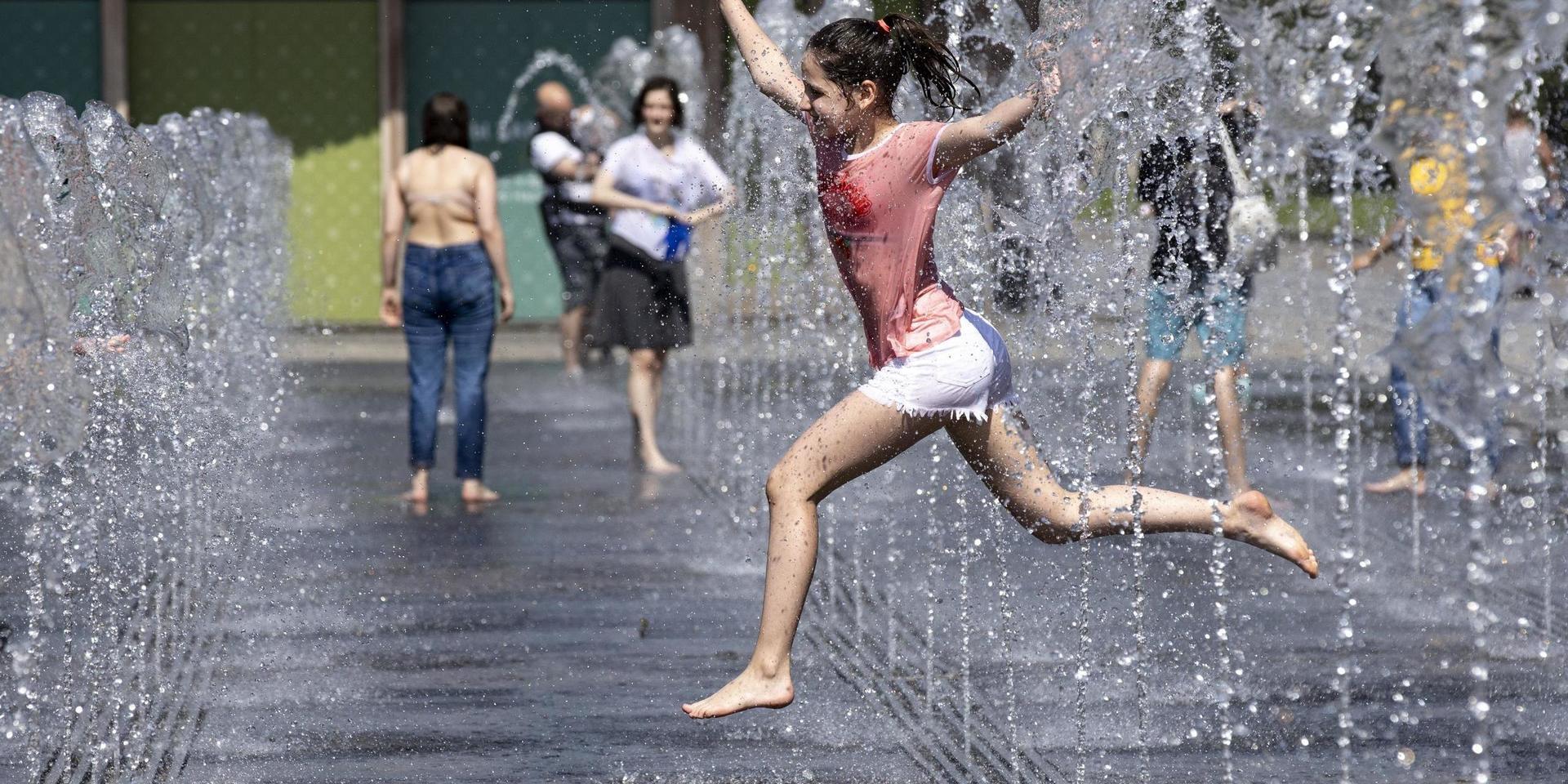 Ett barn svalkar sig i en fontän i Rysslands huvudstad Moskva den 11 juni, när temperaturen låg kring 30 grader. 