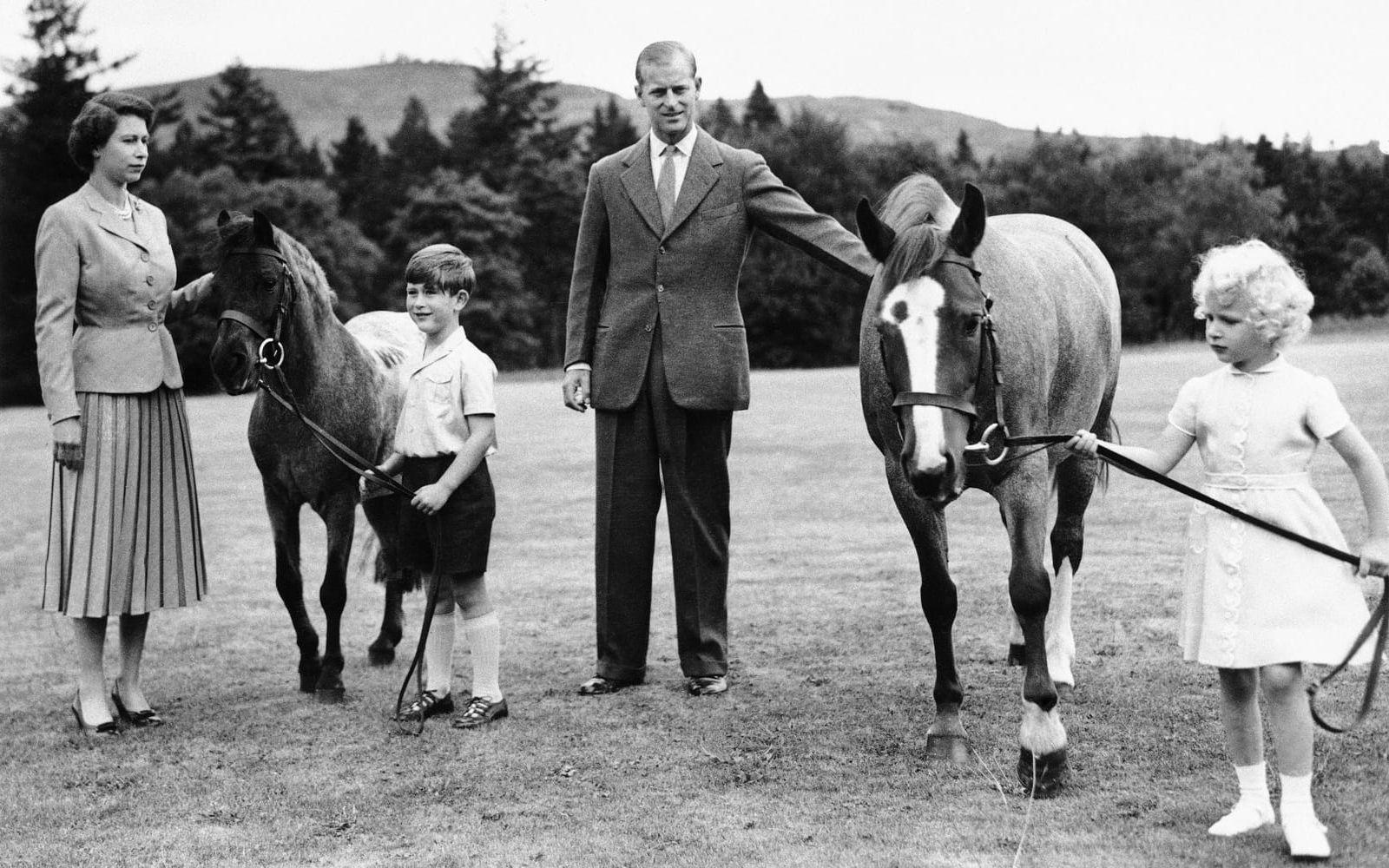 Kungafamiljen har spenderat många somrar i Scottland vid slottet Balmoral. Det gjorde man även sommaren 1955. Här är drottning Elizabeth tillsammans med prins Charles, prins Philip och prinsessan Ann och två av godsets hästar. 