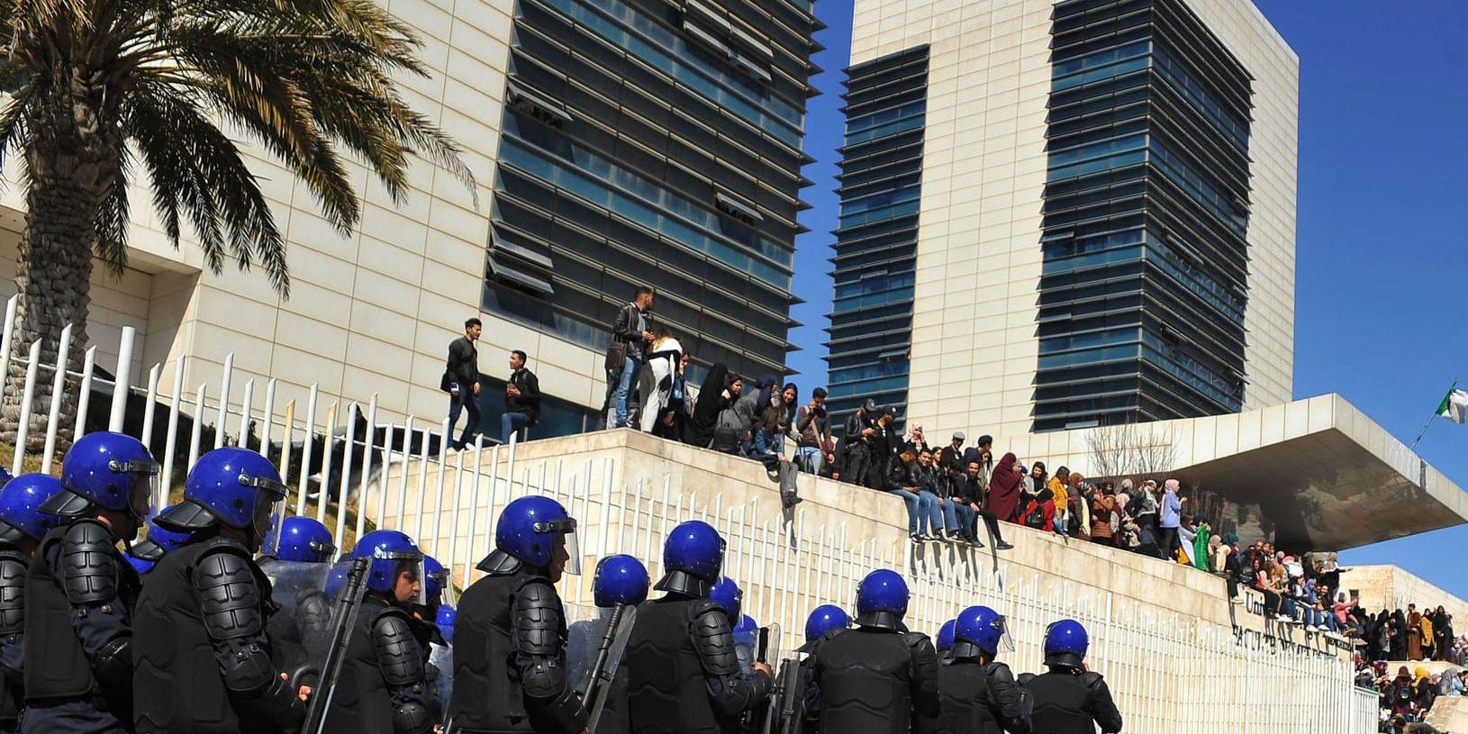 Kravallpolis grupperar sig i Alger, där tiotusentals människor protesterar mot regimen.
