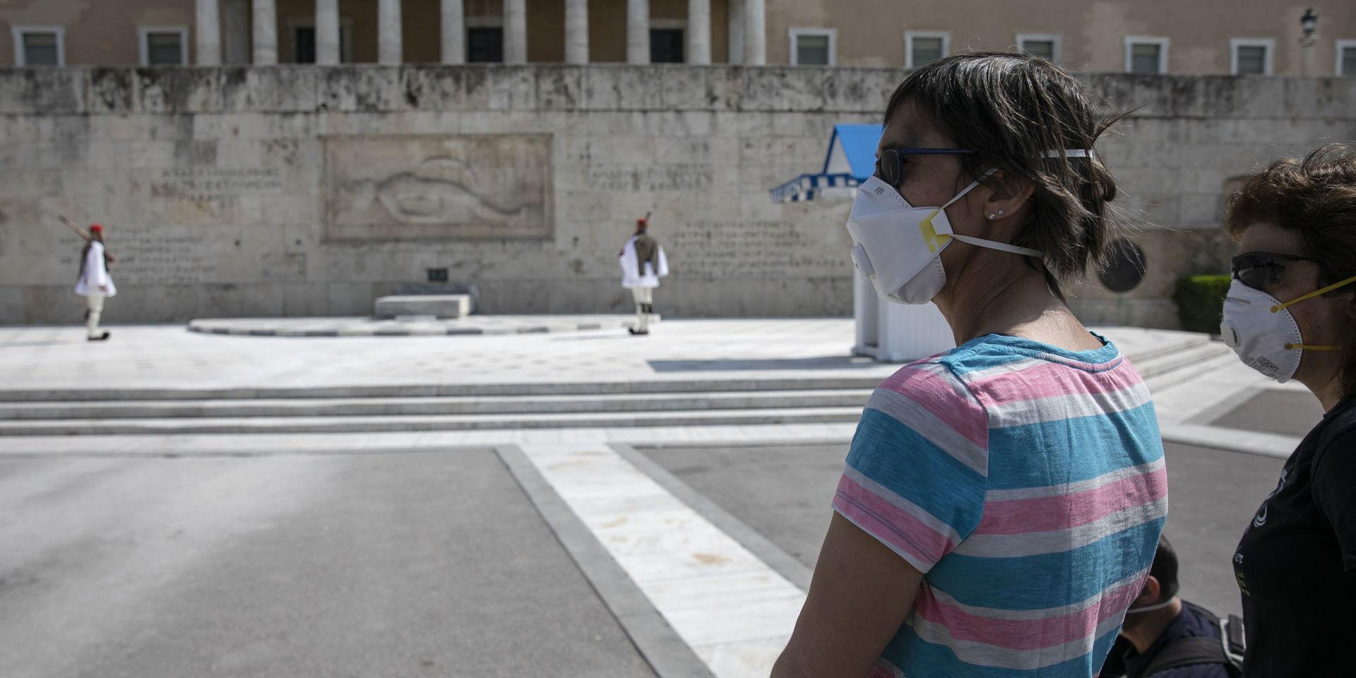 Turister med ansiktsmasker i Aten i mitten av mars – innan utegångsförbudet trädde i kraft.