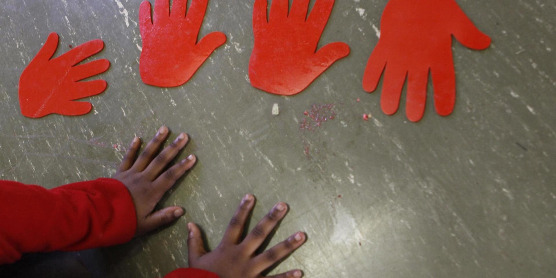A child plays with hand imprints on the floor at a toy library and play center run by Cotlands, a local non-profit organization that promotes early learning opportunities for children, on World Play Day in  Johannesburg, Tuesday, May 28, 2013. Cotlands first opened it's doors 77 years ago offering adoption services for abandoned babies. In 1996 it opened an HIV hospice to address the increased HIV birth rate which claimed 98 children in 2002. In the past three years no child has died leading to the closure of the HIV hospice and now prioritizes it's efforts into advocation for an improvement in early childhood education. (AP Photo/Denis Farrell)