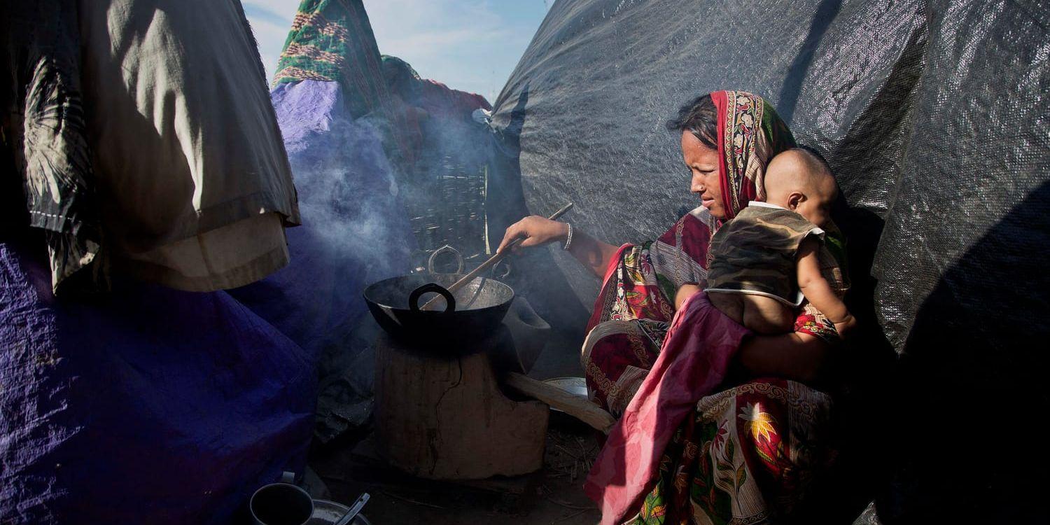 En kvinna lagar mat med en bebis på axeln i den nordöstra delstaten Assam i Indien. Arkivbild.