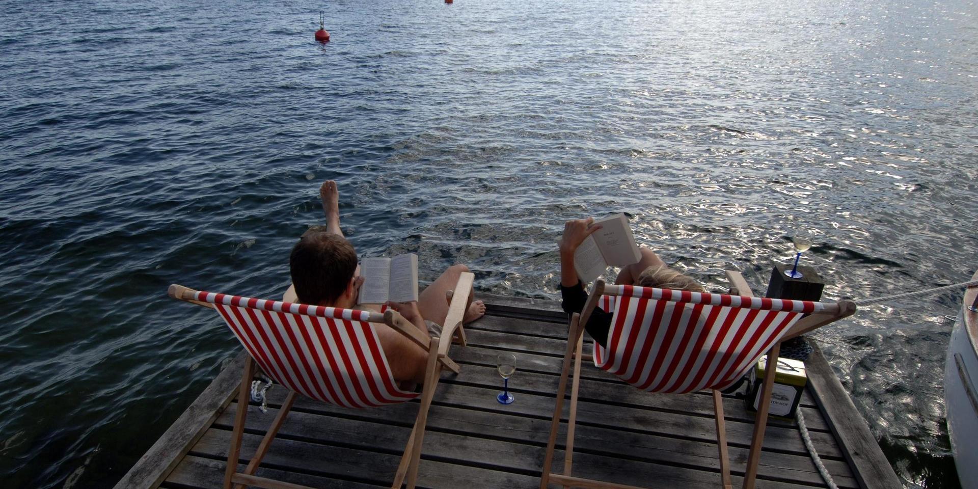 050801. Två ungdomar sitter i varsin solstol på en brygga i Stockholms Skärgård och läser.  Foto. Hasse Holmberg. Kod 96  COPYRIGHT SCANPIX SWEDEN