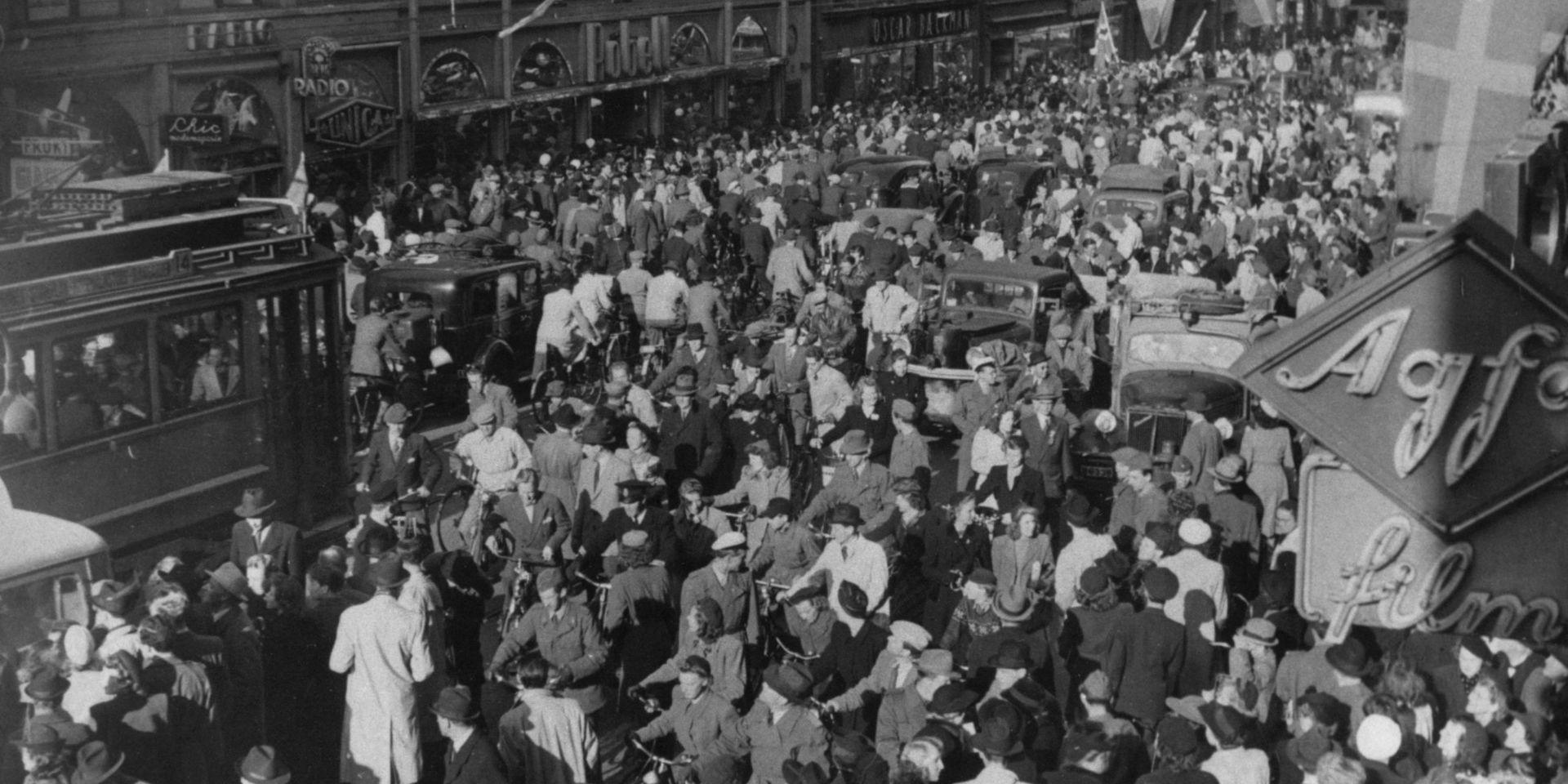 Fredsdagen 1945 på Kungsgatan i Stockholm. 
Jublande folkmassor på gatan. Sett ovanifrån.
Spårvagn försöker forcera folkmassan.
