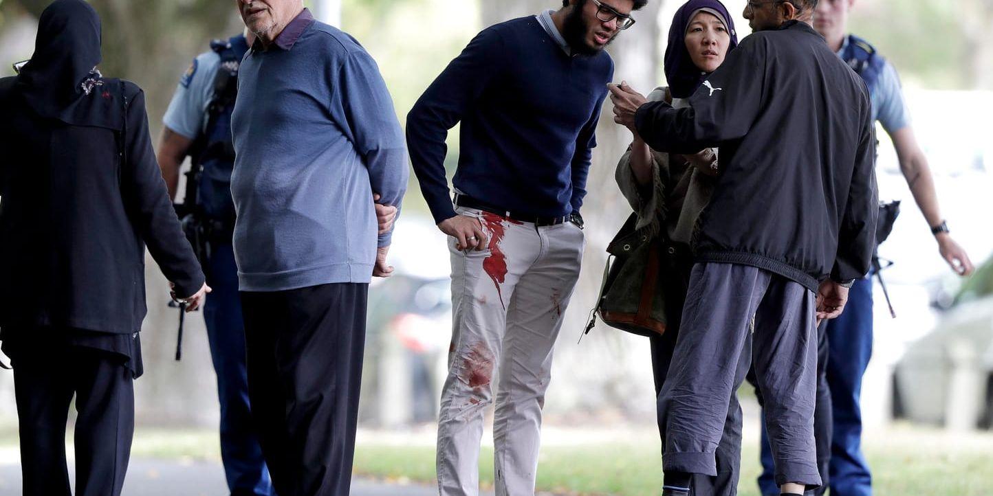 Människor står utanför en av de moskéer som attackerats i Christchurch på fredagen.