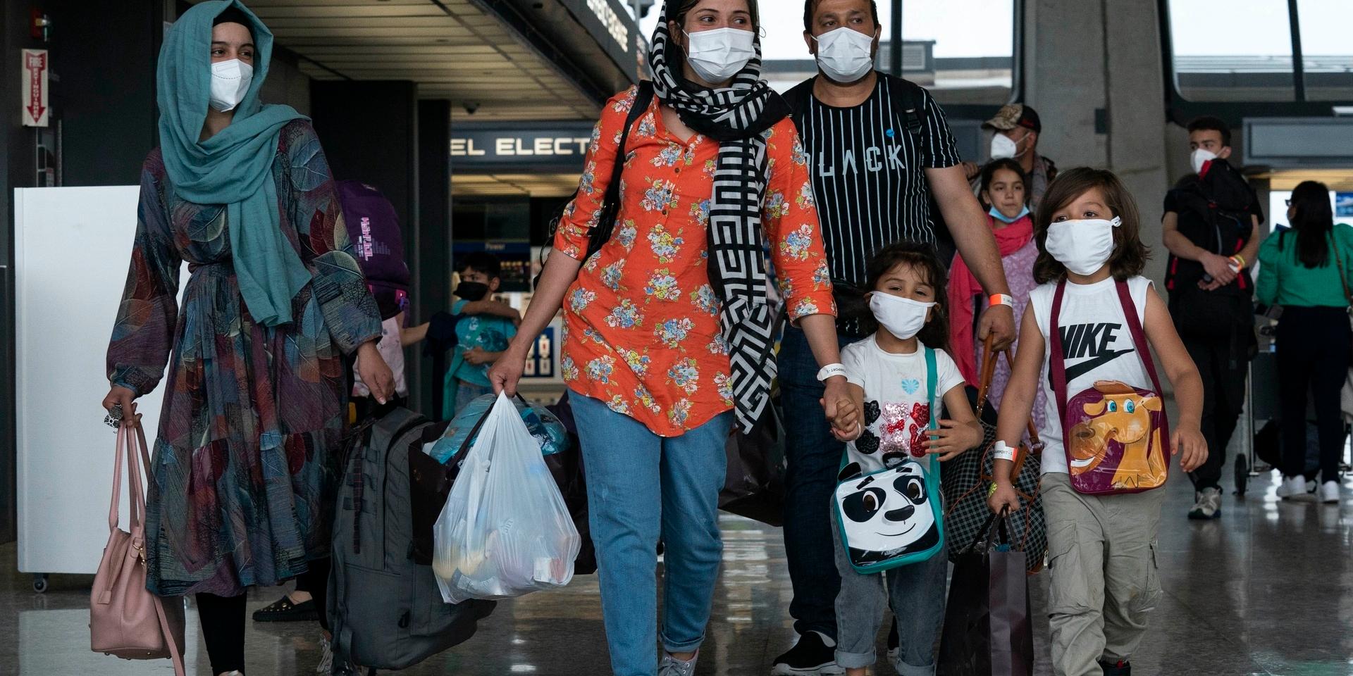 Families evacuated from Kabul, Afghanistan, walk through the terminal to board a bus after they arrived at Washington Dulles International Airport, in Chantilly, Va., on Sunday, Aug. 29, 2021. (AP Photo/Jose Luis Magana)  VAJL118