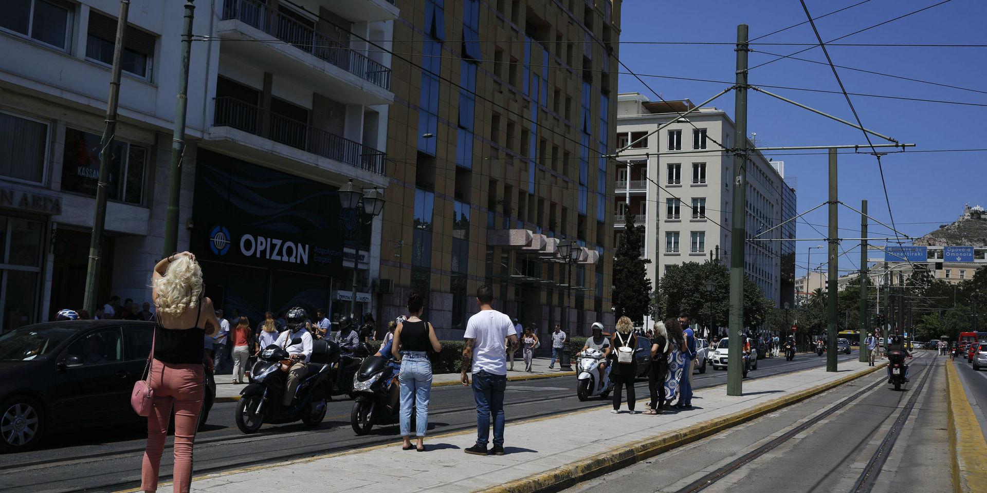 Människor på gatan utanför en byggnad i Aten efter fredagens skalv.