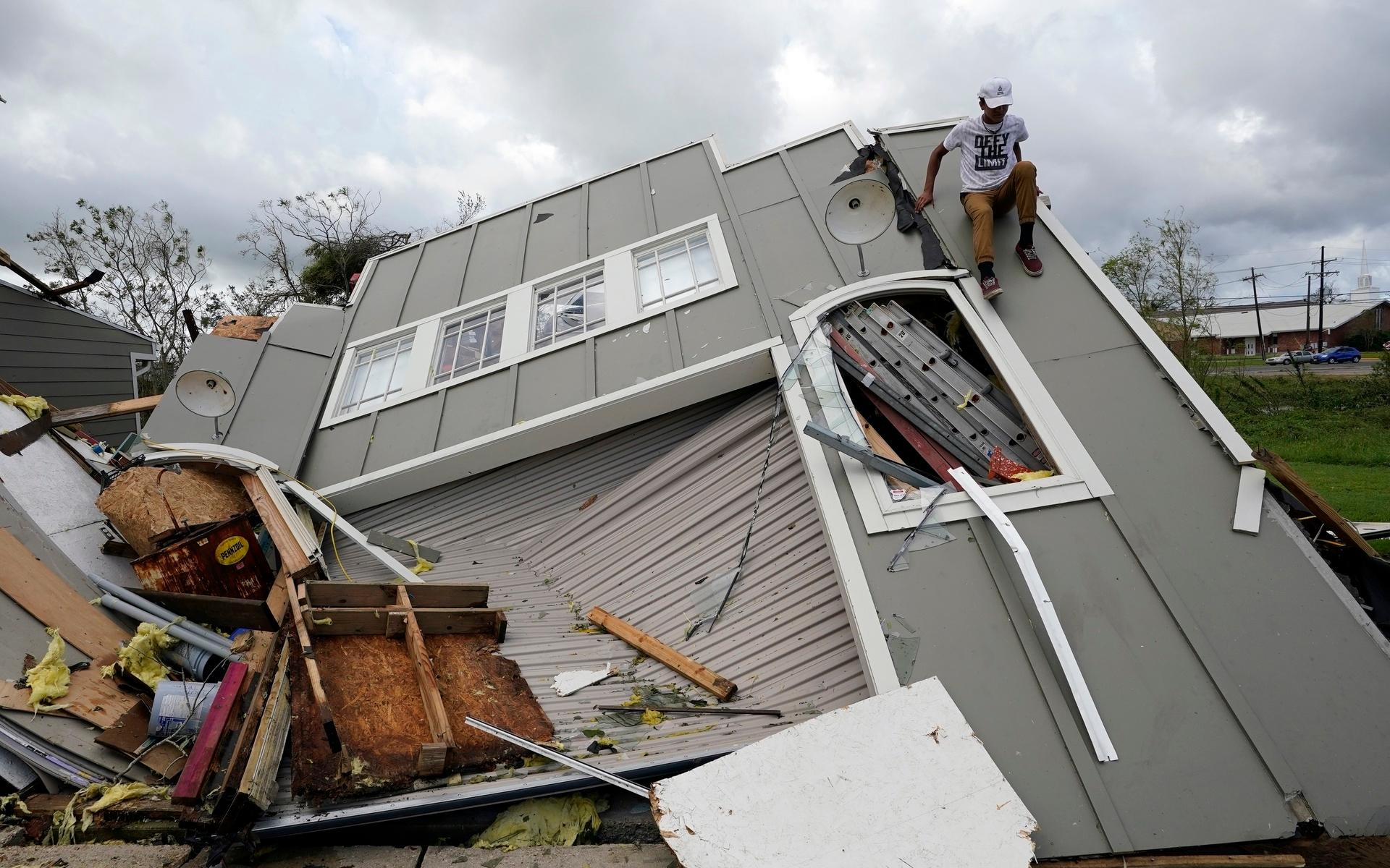 Jeremy Hodges klättrar ner från sitt hem som förstörts efter orkanen Ida under måndagen.