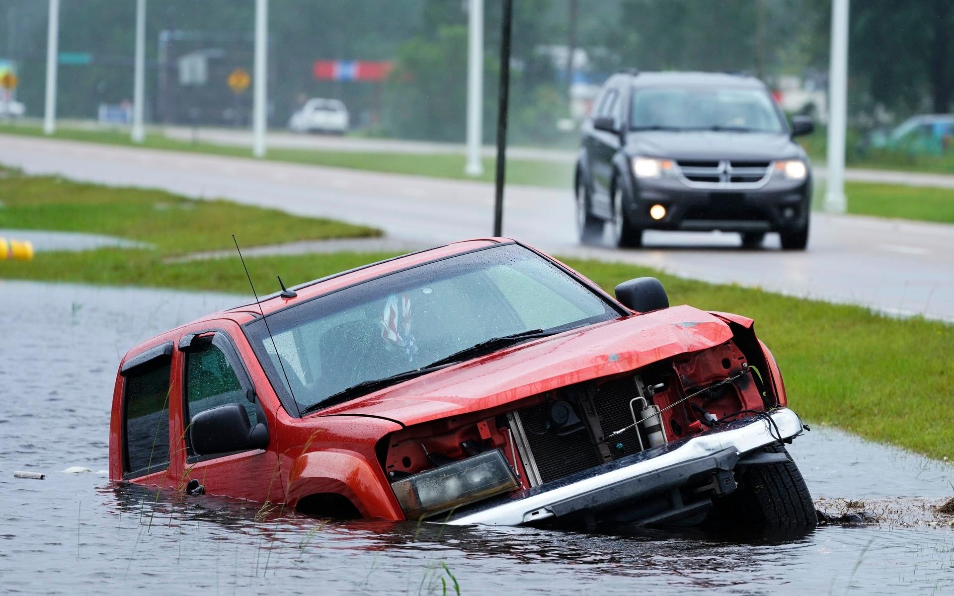 En övergiven bil hade sjunkit ned i vattnet nära en översvämmad motorväg.