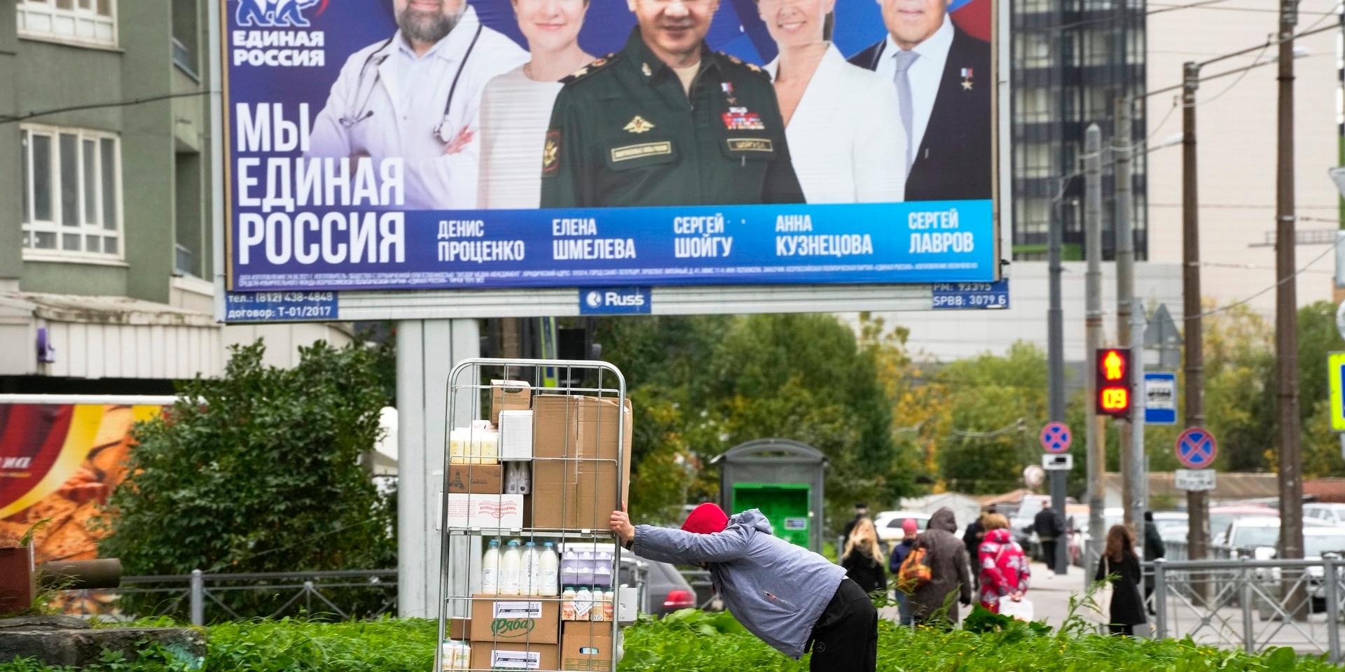 Under en valaffisch från maktpartiet Enade Ryssland syns en person som knuffar en vagn med matvaror. Rysslands ekonomi dras med hög inflation, särskilt mycket ökar matpriserna.