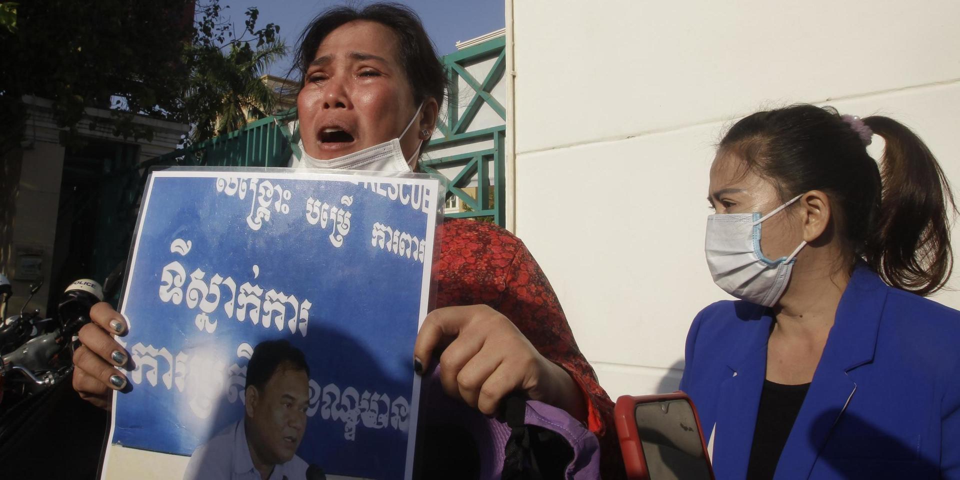 Prum Chenda, som är gift med en fängslad oppositionell aktivist, håller upp en bild på sin man utanför domstolen i Phnom Penh.