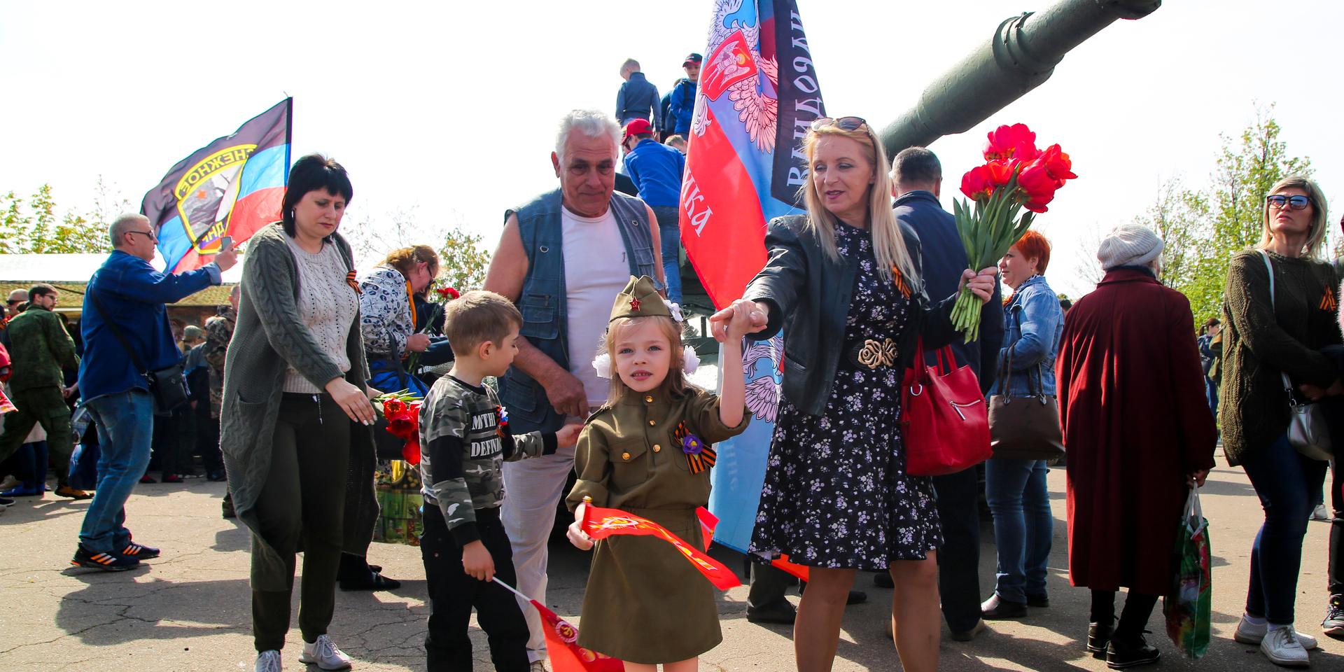 A girl wearing Soviet-era military uniform and her relative walks past a cannon during celebrations of the Victory Day at a World War II memorial in Saur-Mogila, about 60 km (31 miles) east of Donetsk, eastern Ukraine, Saturday, May 8, 2021. Efforts have stalled to end the conflict between Russia-backed rebels and Ukrainian forces, which has killed more than 14,000 people since it broke out in 2014. Russia, which claims it has no military presence in eastern Ukraine, fueled the tensions this year by massing troops and conducting large-scale military exercises near its border with Ukraine. (AP Photo/Alexei Alexandrov)  XAZ102